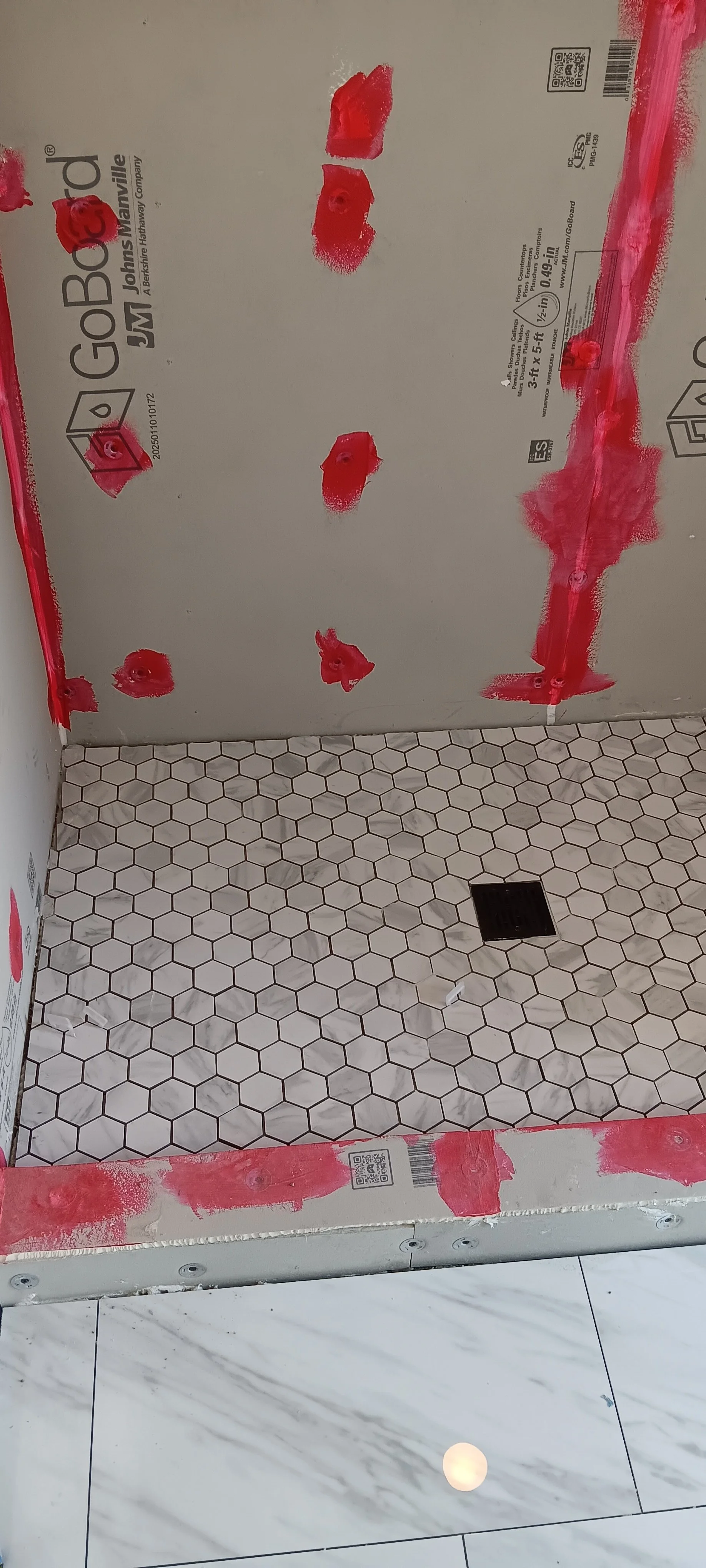 Waterproof shower walls and mosaic floor prepared for tile installation.