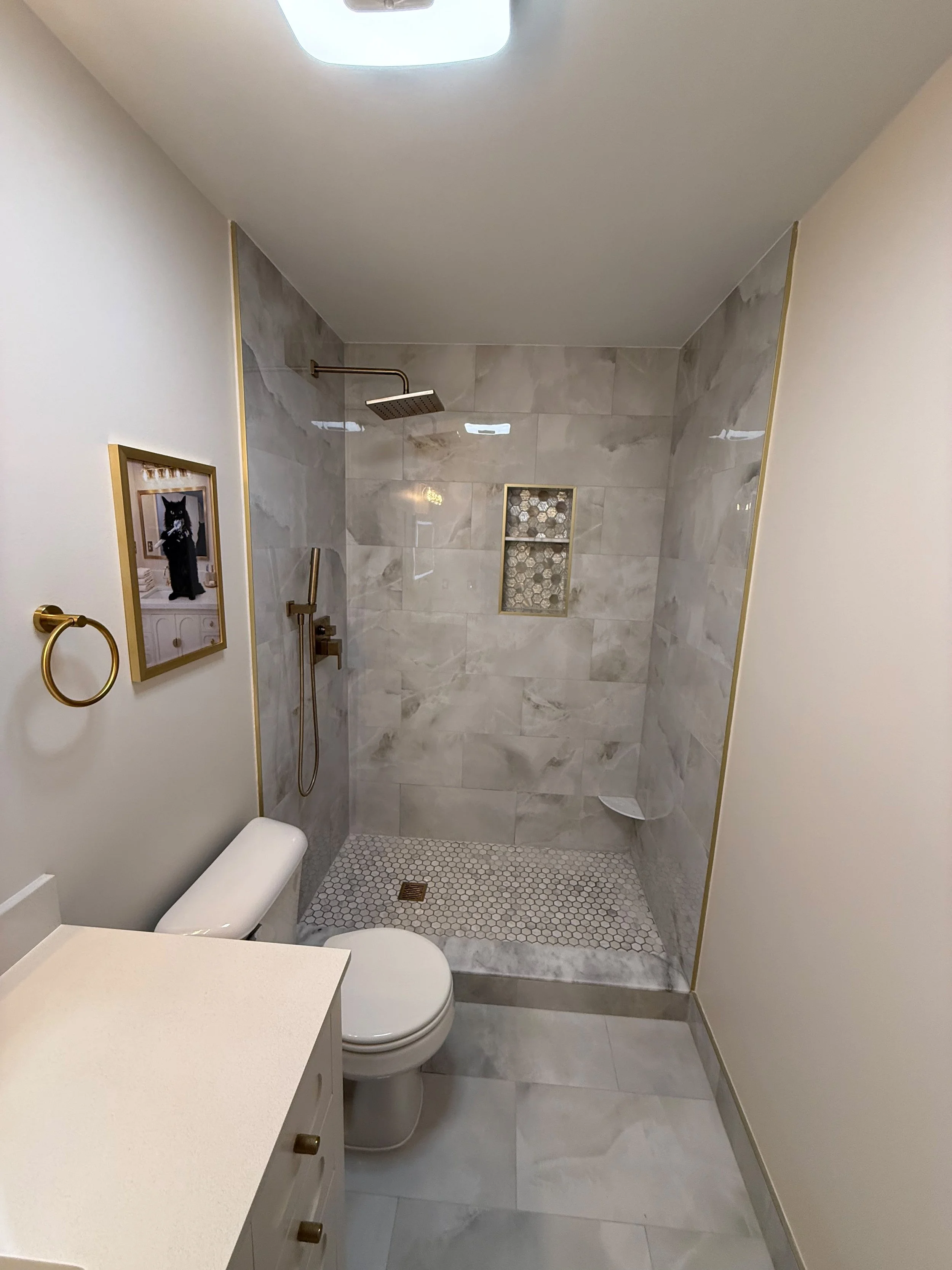 Complete bathroom layout showcasing a curbless shower, spacious floor plan, custom tile installation, floating-style vanity, and coordinated gray finishes throughout.
