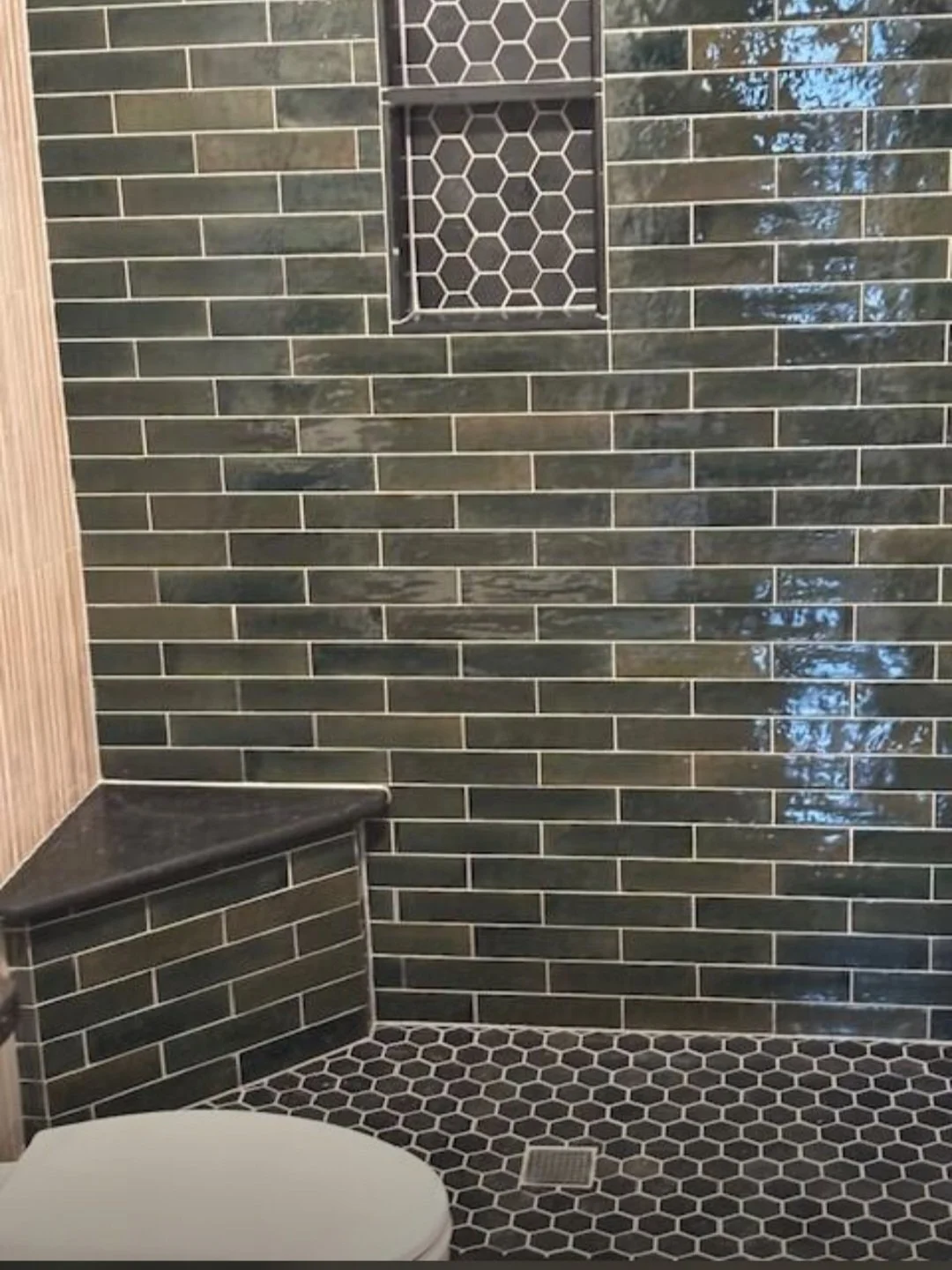 A close-up of the custom tile installation highlights the detailed niche, premium grout work, and precision craftsmanship.