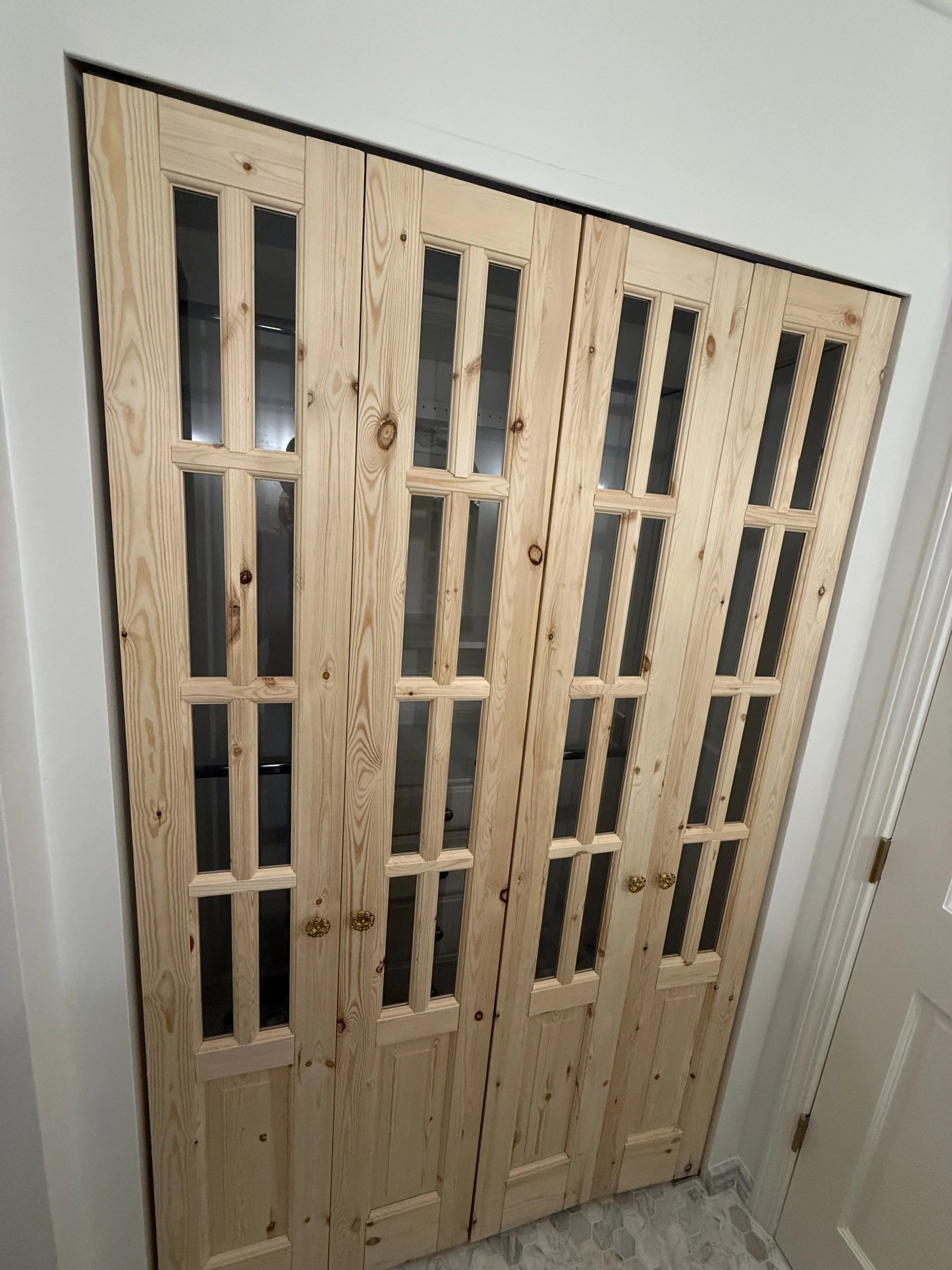 Natural wood glass-panel door installed as a decorative feature in a remodeled bathroom.