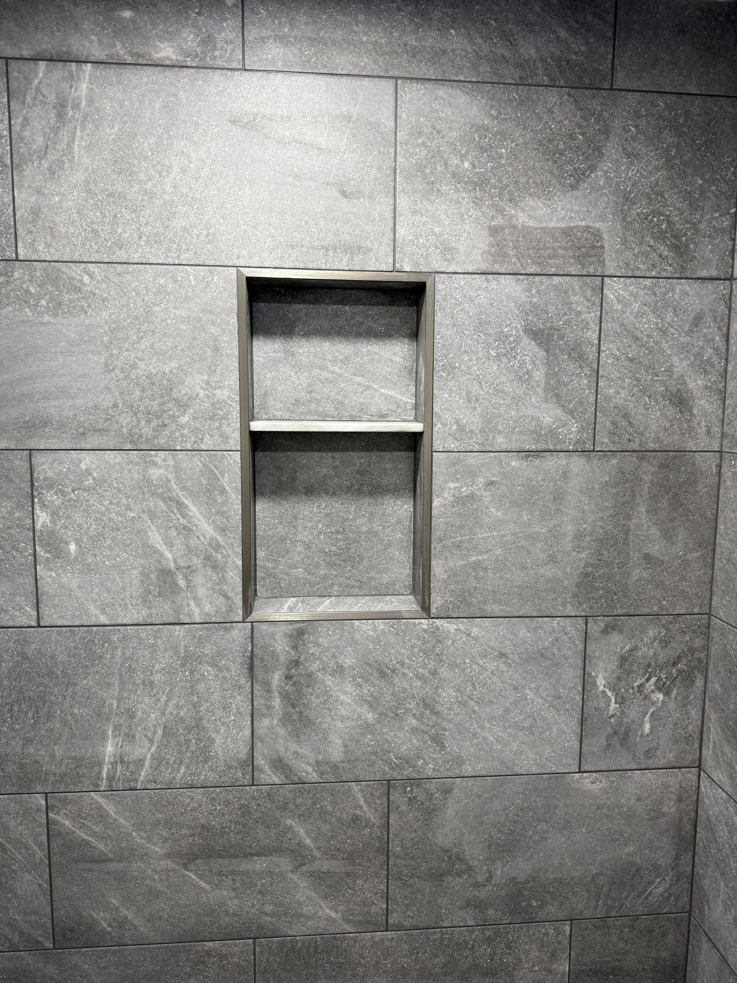 A built-in shower niche finished with large-format tile, providing convenient storage while adding a sleek, contemporary look.