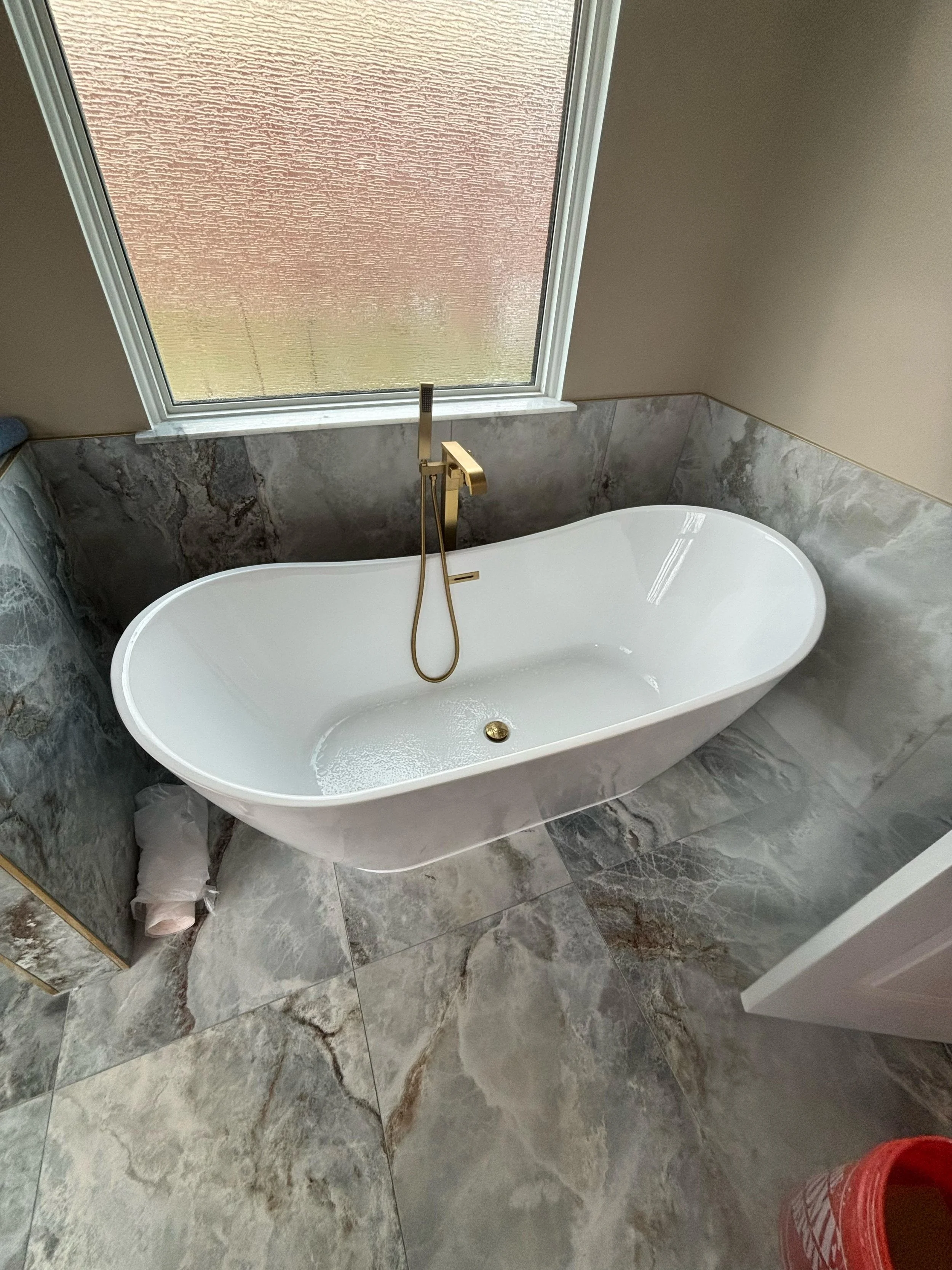 This complete bathroom renovation includes a beautiful soaking tub, custom tile shower, premium porcelain tile flooring, and elegant fixtures designed to provide lasting quality and modern appeal.
