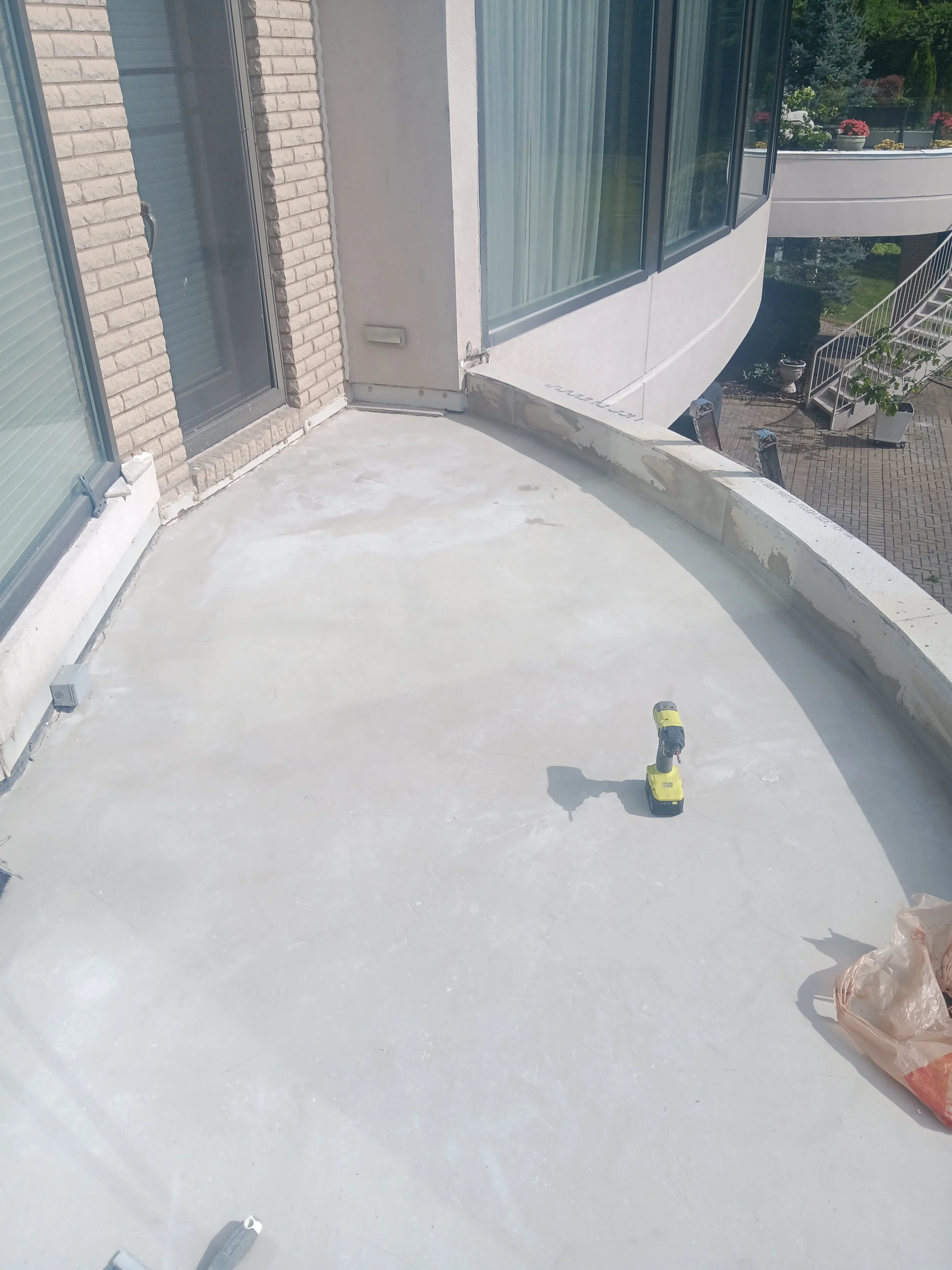 Restored curved balcony floor with a smooth waterproof finish and clean edges along the exterior wall.