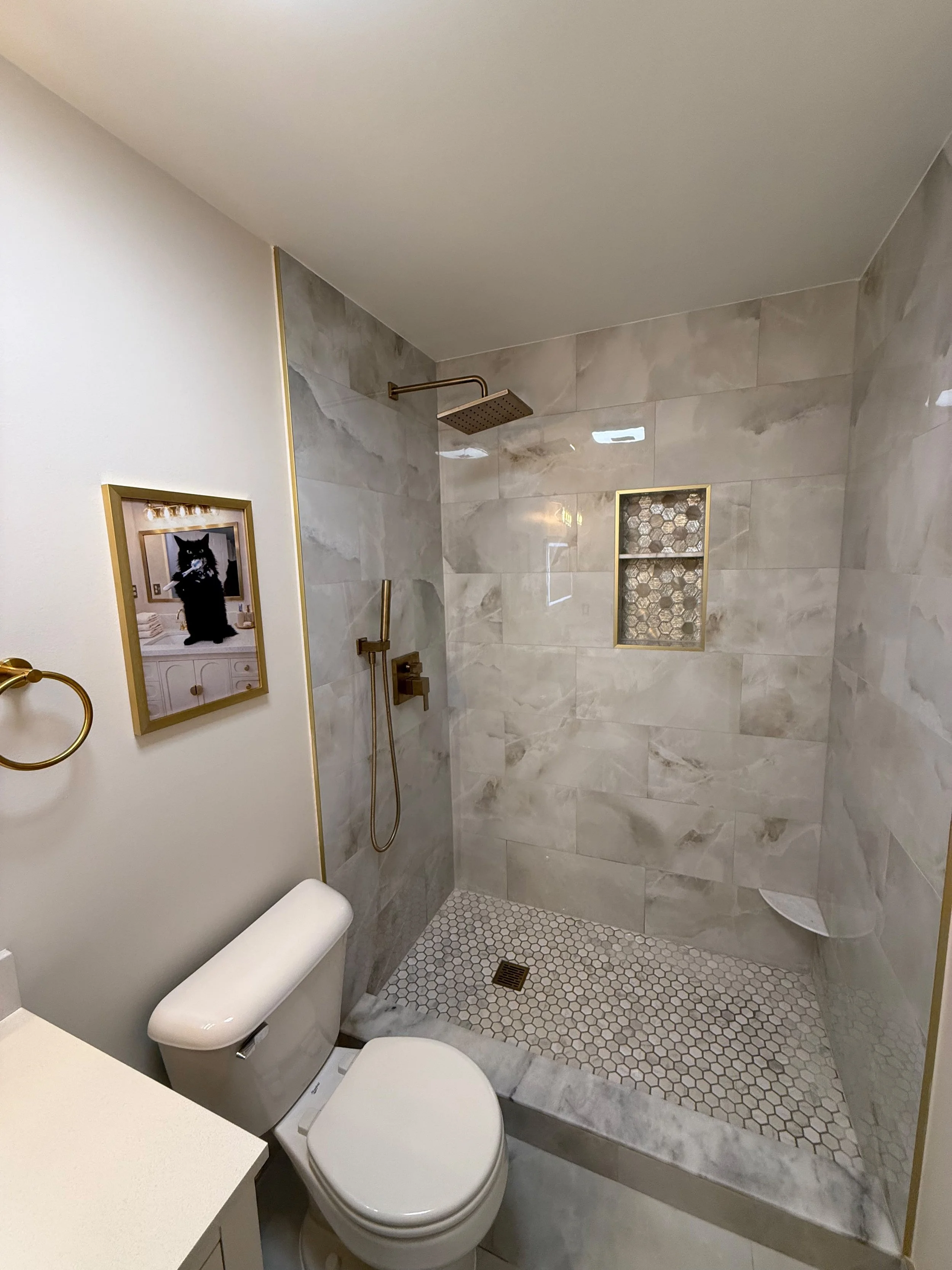 Contemporary bathroom with an open walk-in shower, modern toilet, decorative recessed wall niche, textured shower floor, and sleek black plumbing fixtures.