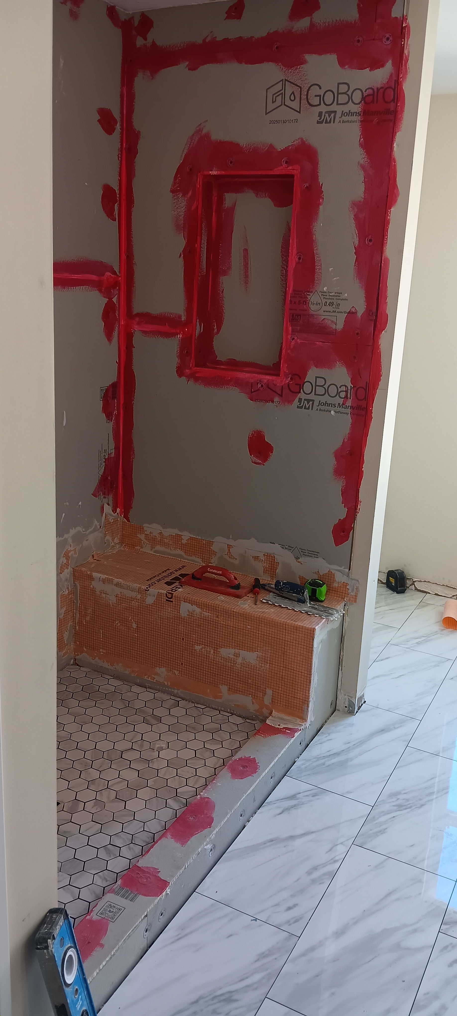 Waterproofed shower entrance and built-in bench ready for finishing tile.