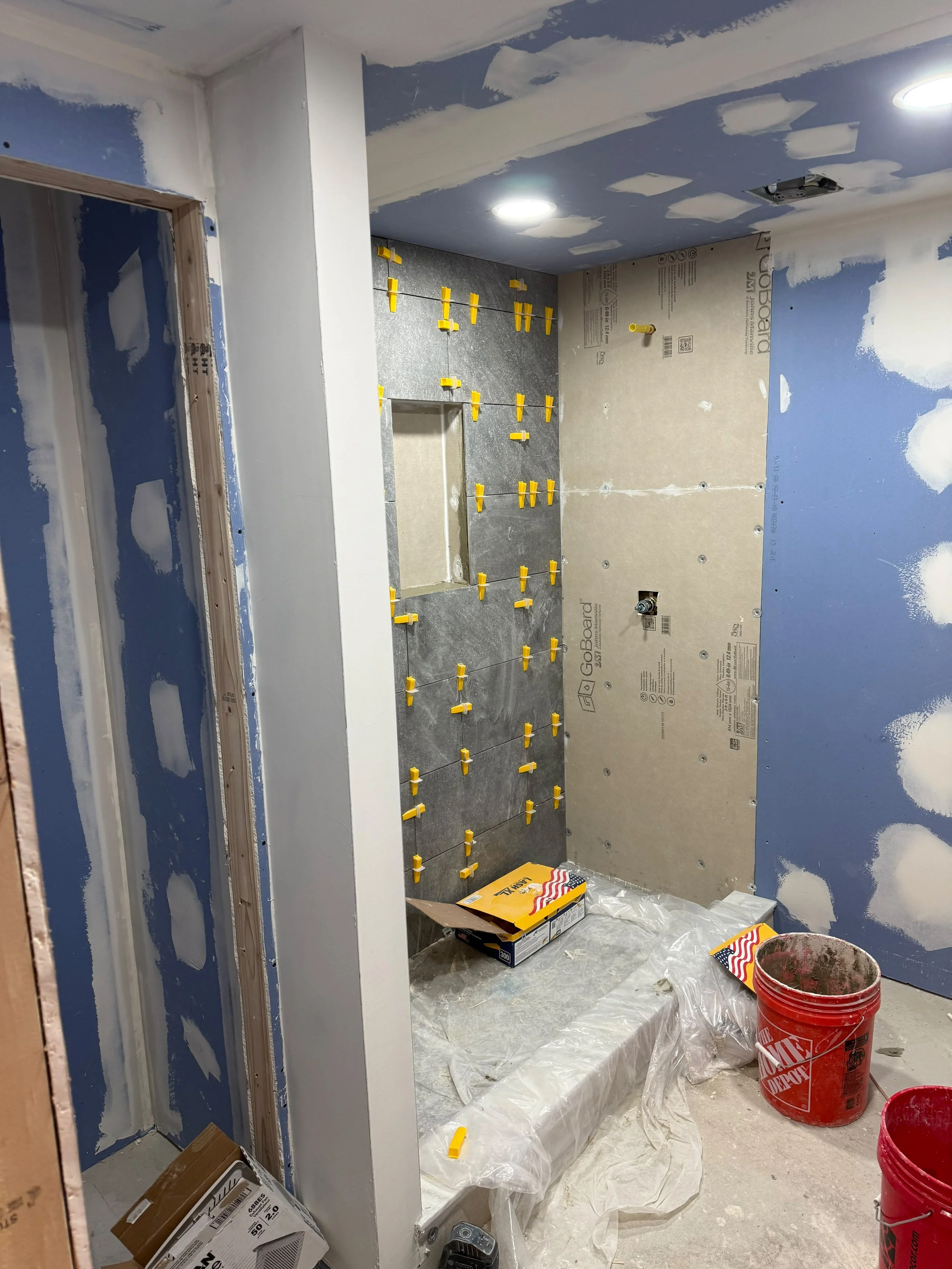 The bathroom renovation is coming together with expertly installed tile, smooth wall finishes, and careful attention to every detail.