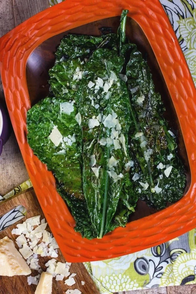Grilled or roasted leafy greens topped with crumbled white cheese, served in an orange basket.