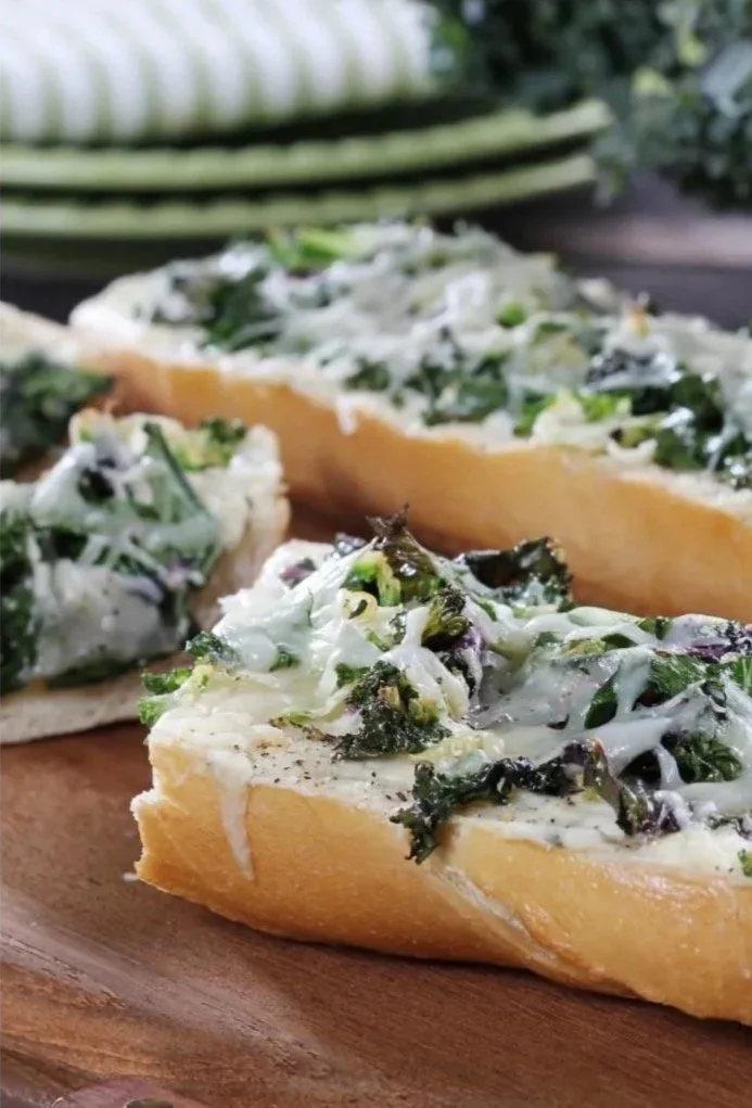 Slices of vegetable pizza with leafy greens and cheese on a wooden platter.