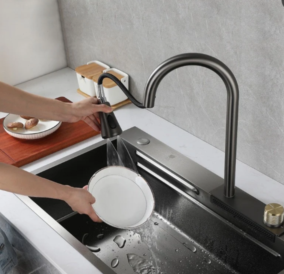 Person rinsing a white plate in a modern kitchen sink under a black faucet.