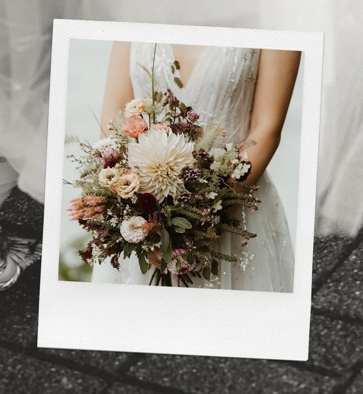 Photograph of a wedding bride holding a bouquet of pink, white, and purple flowers.