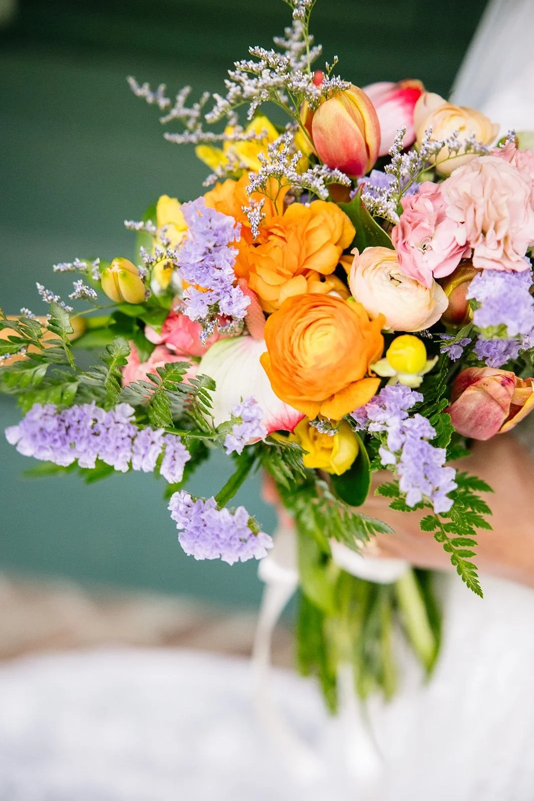 Close-up of a colorful bouquet of various flowers, including orange, yellow, pink, and purple blooms with greenery.