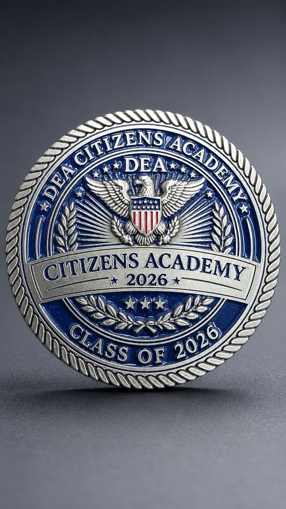 A round badge with a shield and eagle emblem, blue and silver colors, inscribed with "DEA Citizens Academy 2026, Class of 2026."