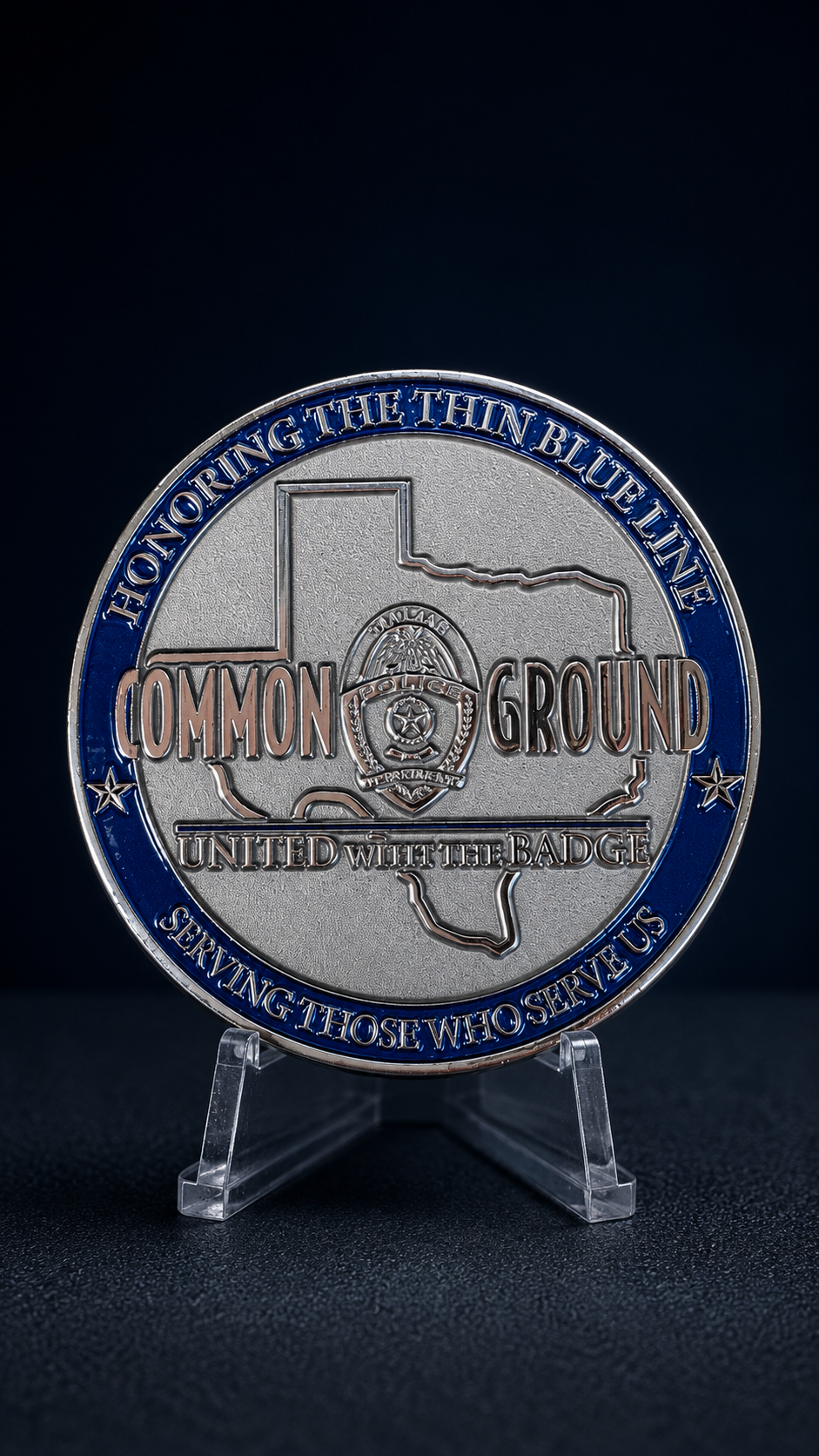 A police badge-shaped commemorative coin with the outline of Texas, featuring the words 'Common Ground' and 'United with the Badge,' and the phrase 'Honoring the blue line' around the border, celebrating law enforcement service.