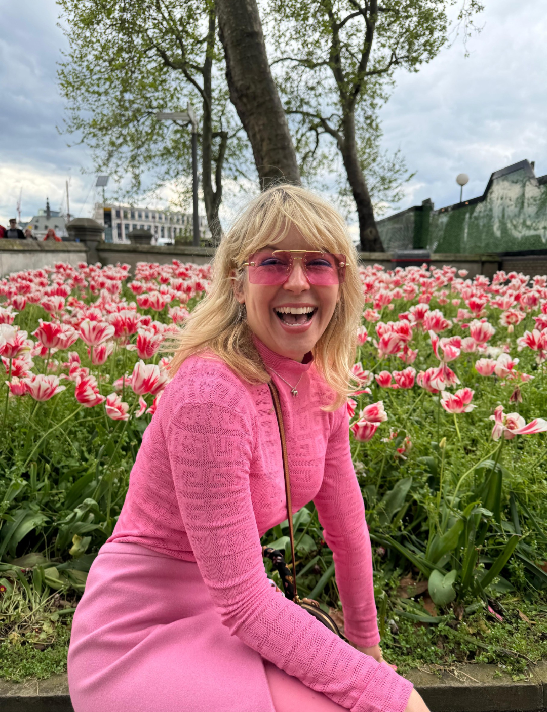 Camilla smiling in a field of flowers dressed in pink