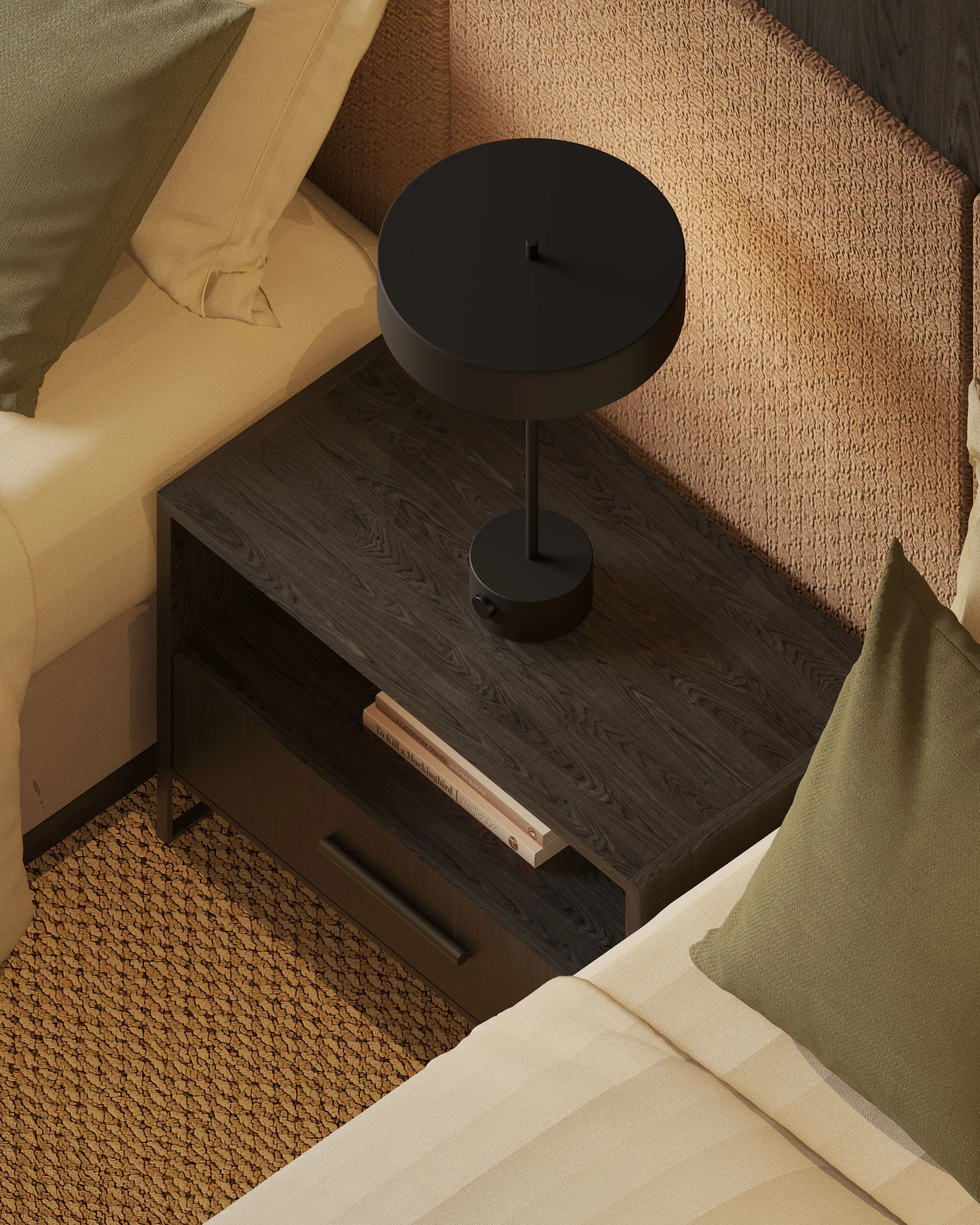 A round black bedside table with a small central knob, placed next to a beige bed and a textured orange armchair, on a dark wooden floor and a patterned beige carpet.