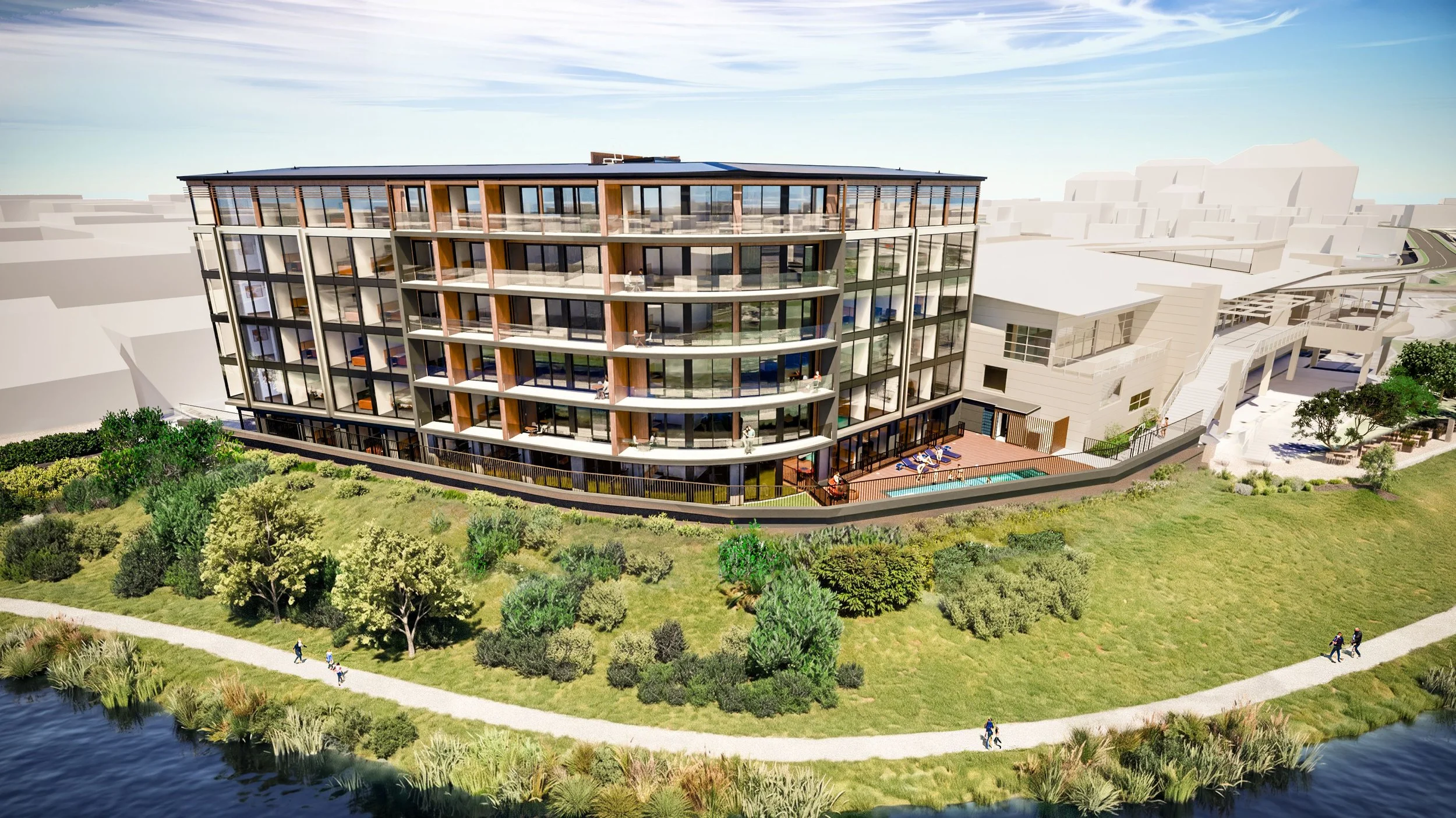 A modern multi-story residential building with glass balconies, surrounded by greenery and a walking path along a small water body.