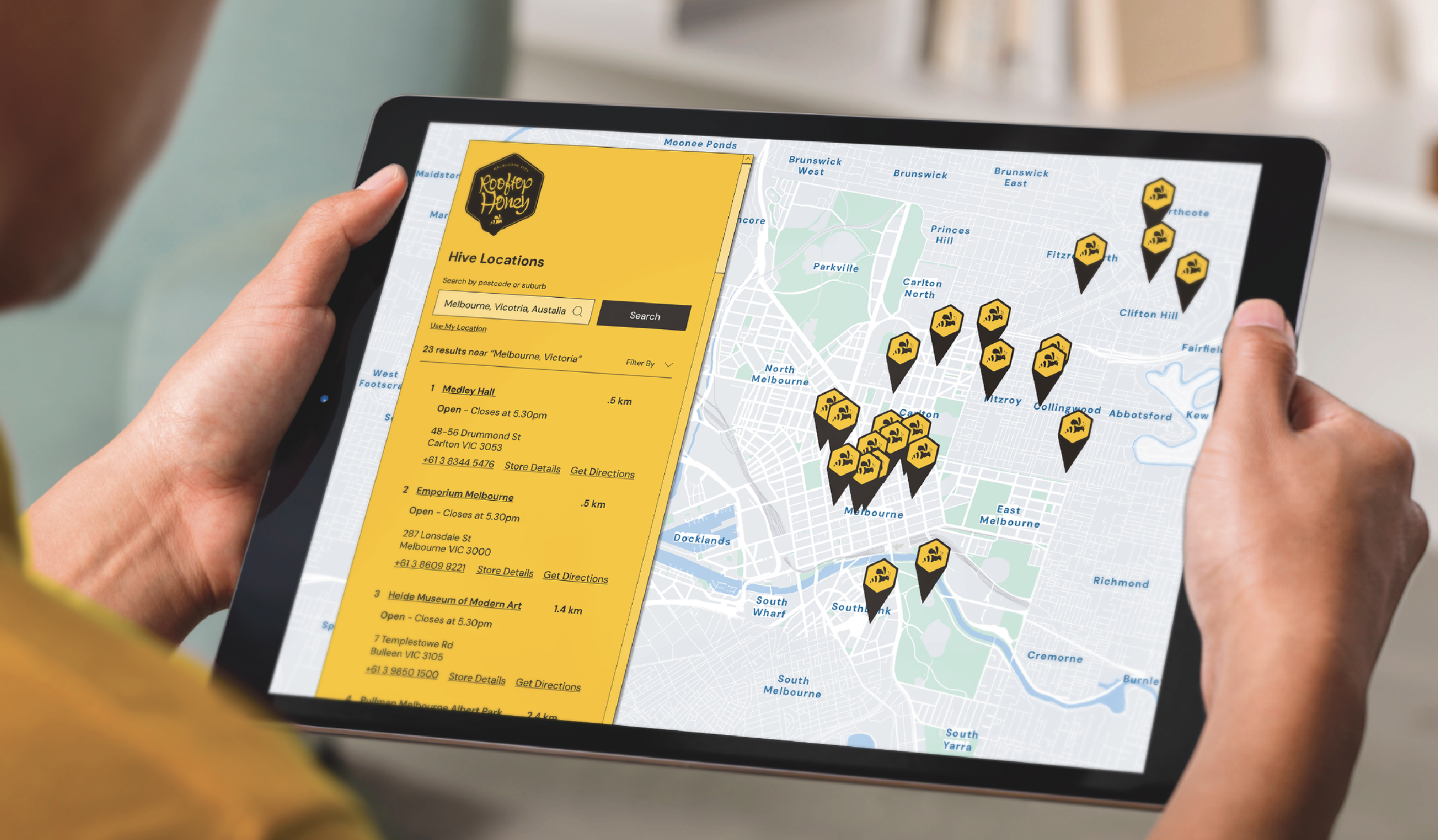 A person holding a tablet displaying a map of Melbourne, Australia, with multiple markers indicating hive locations. A yellow panel on the left side lists hive details with search options.