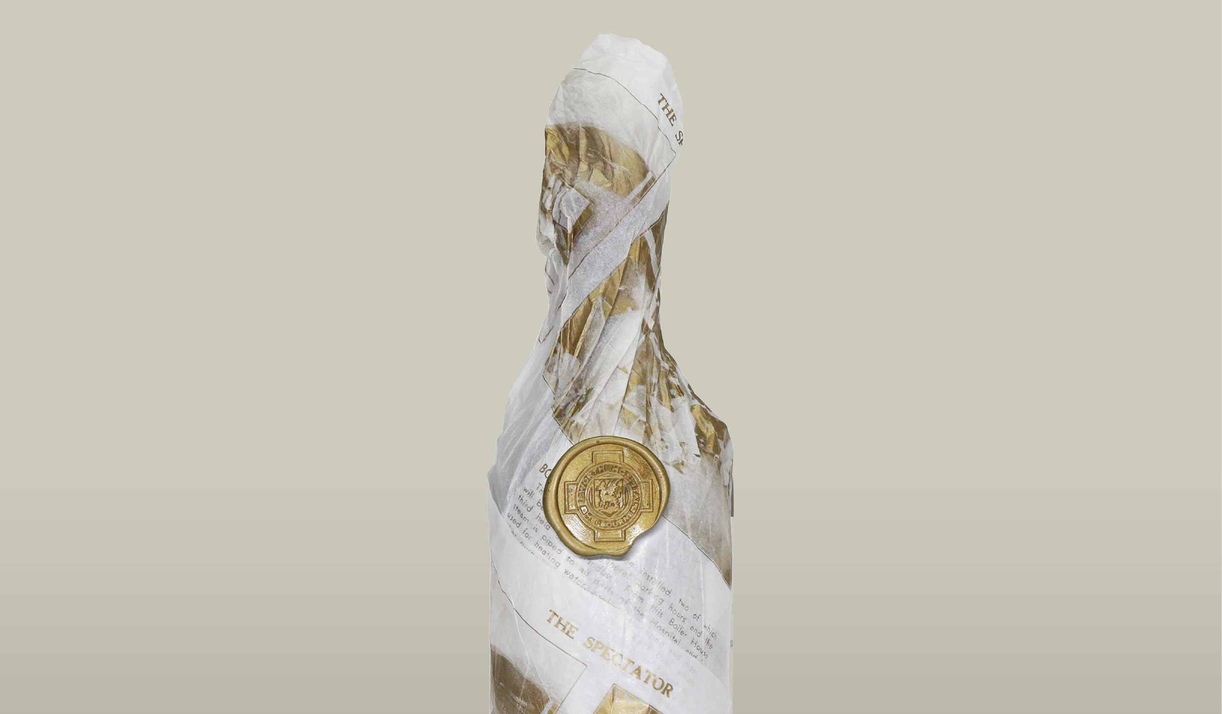 A gold-colored medal embedded in crumpled newspaper with text reading 'The Spectator' and a decorative emblem.
