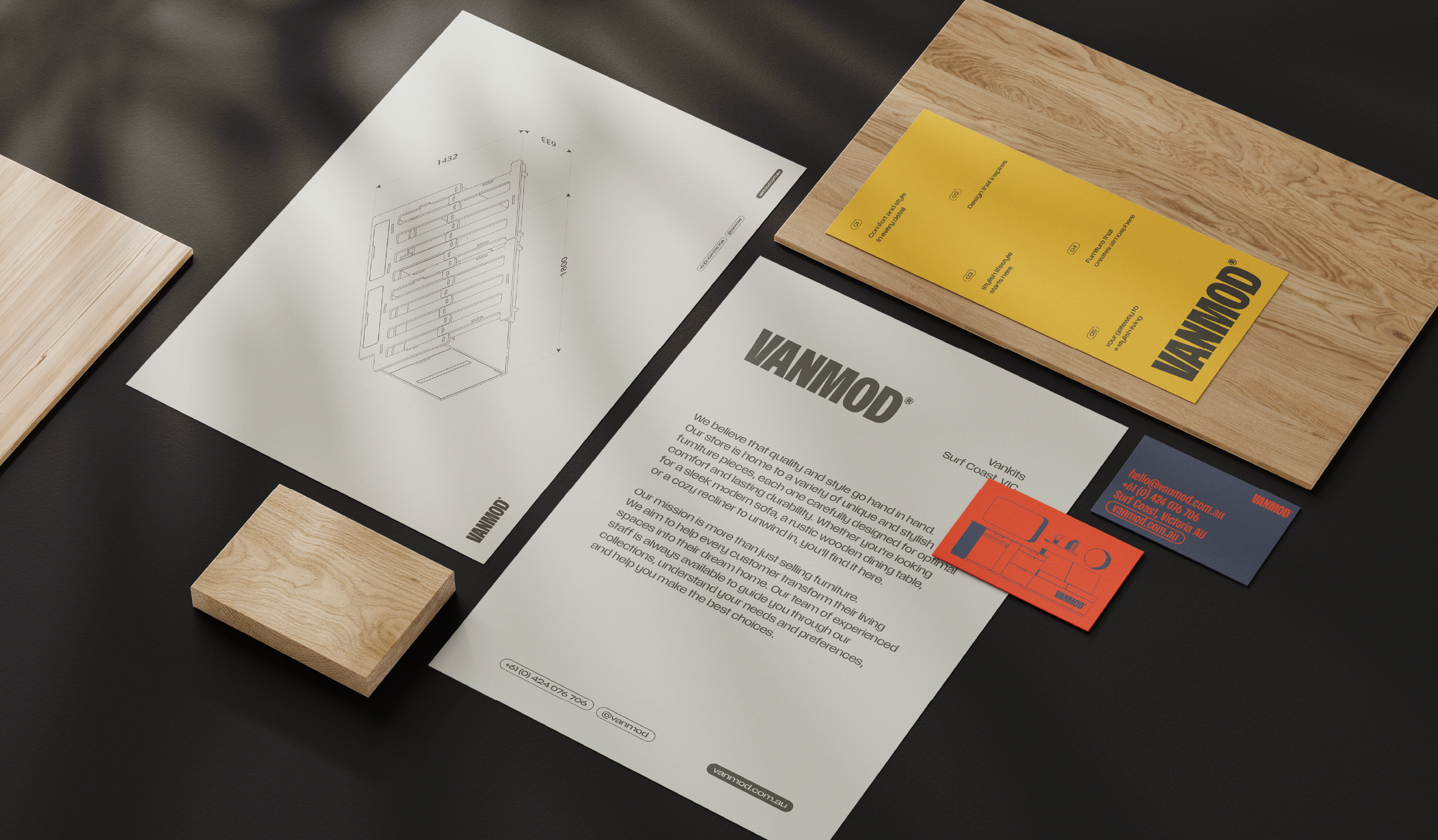 Documentation and sample pieces for furniture design, including a technical drawing of a furniture piece, a yellow informational card with text, a wood sample, and business cards, all arranged on a dark surface.