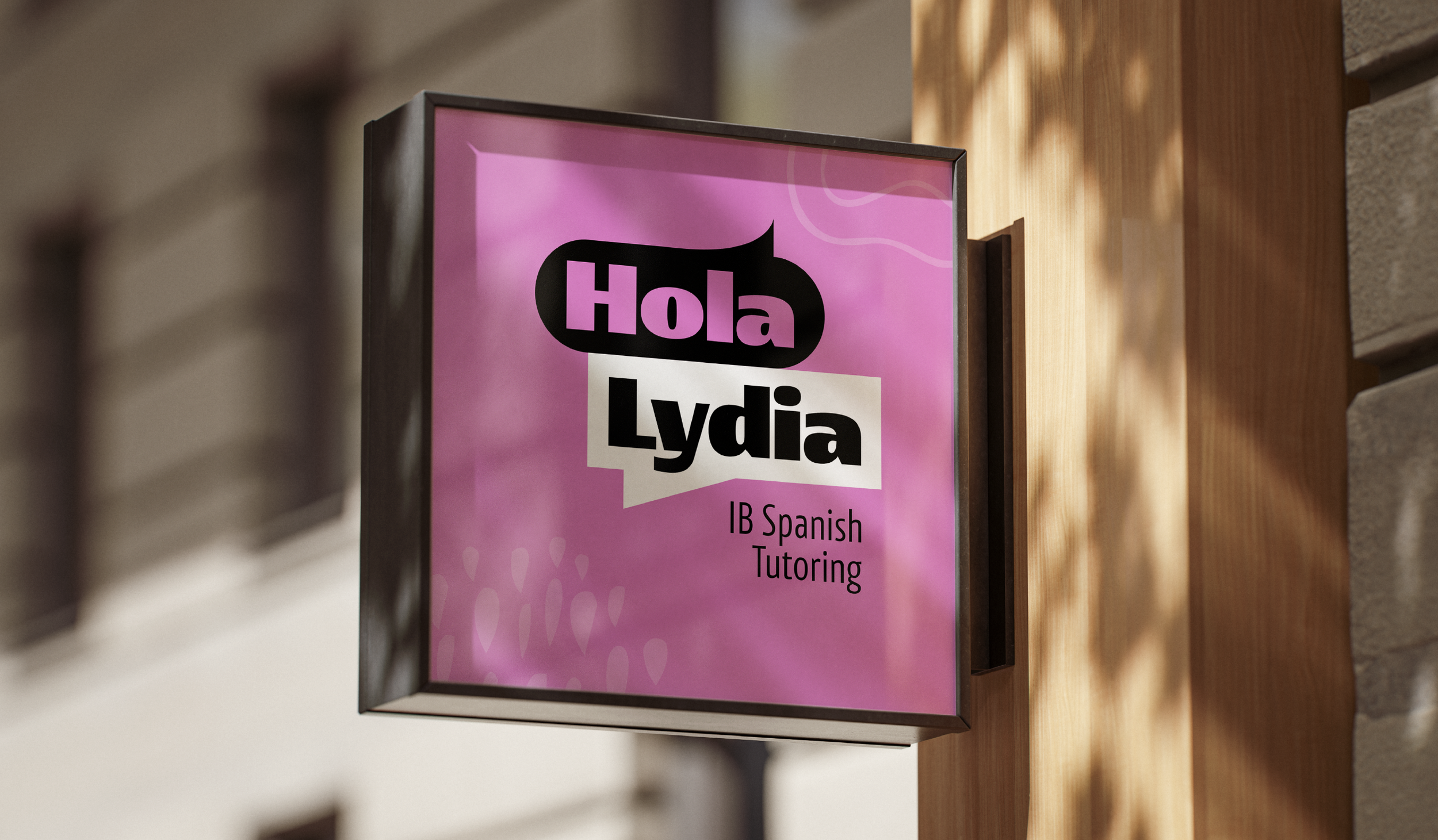 Pink sign on a wooden wall advertising Lydia's IB Spanish Tutoring.