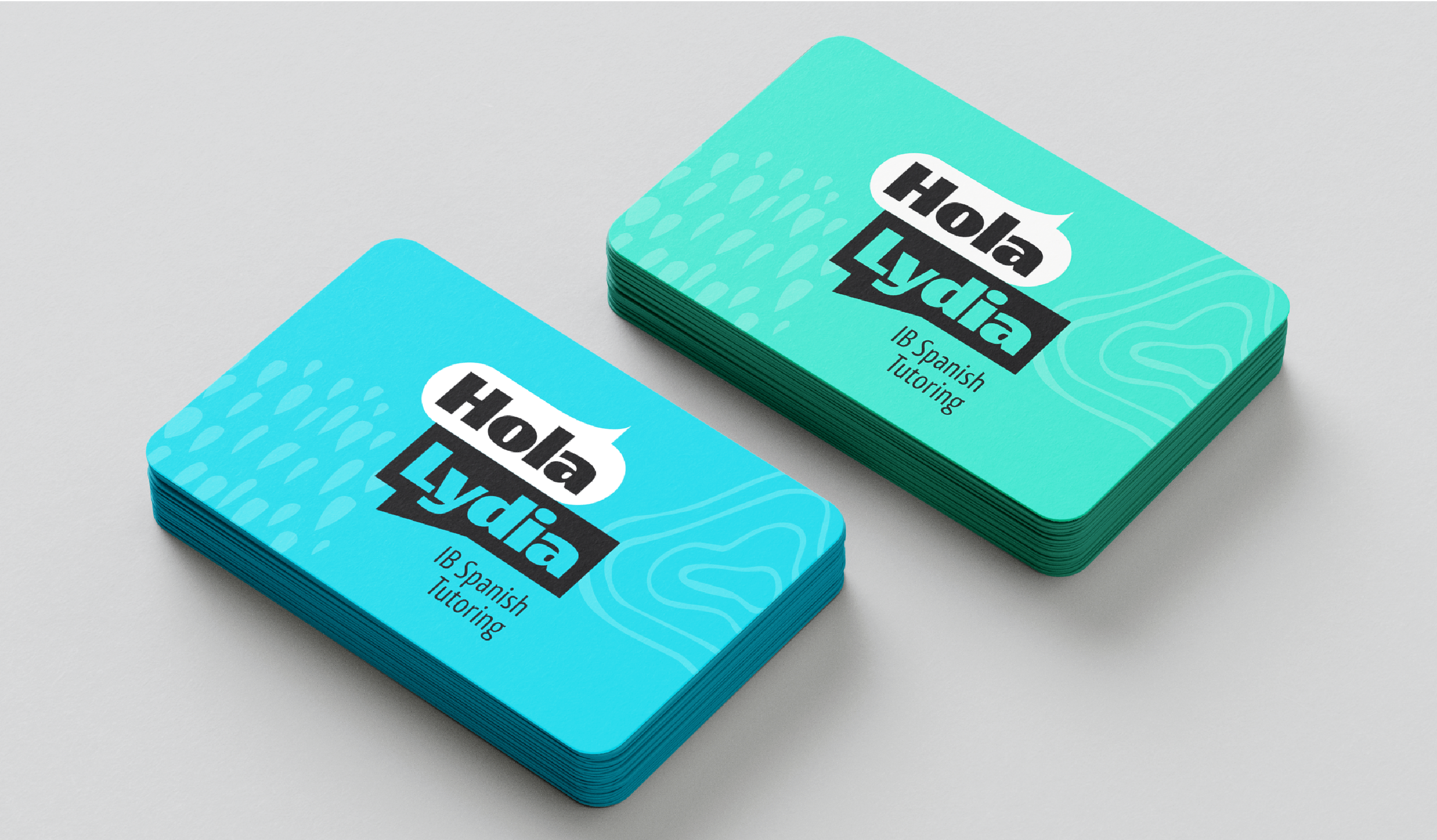 Stacks of blue and green business cards for Hola Lydia, a Spanish tutoring service, on a white surface.