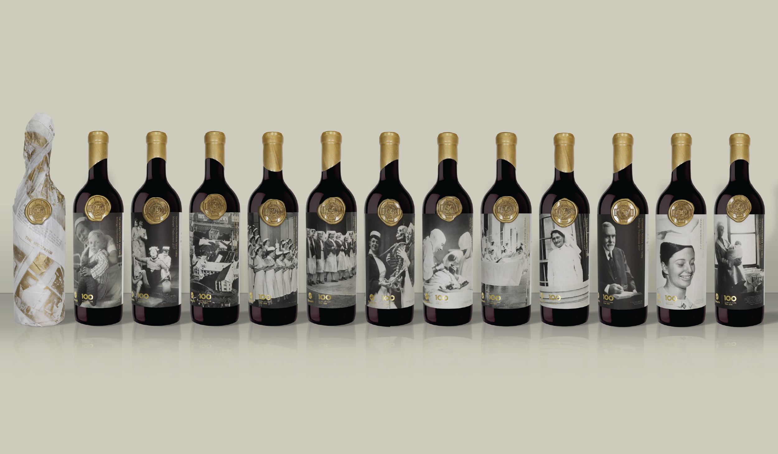A row of wine bottles wrapped in paper and featuring black-and-white historical photographs on their labels, with each label depicting different scenes and people.