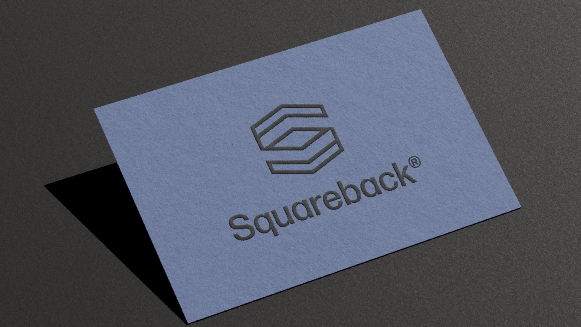A printed business card with the Squareback logo featuring a geometric hexagon shape and the word 'Squareback' beneath it, placed on a dark surface.