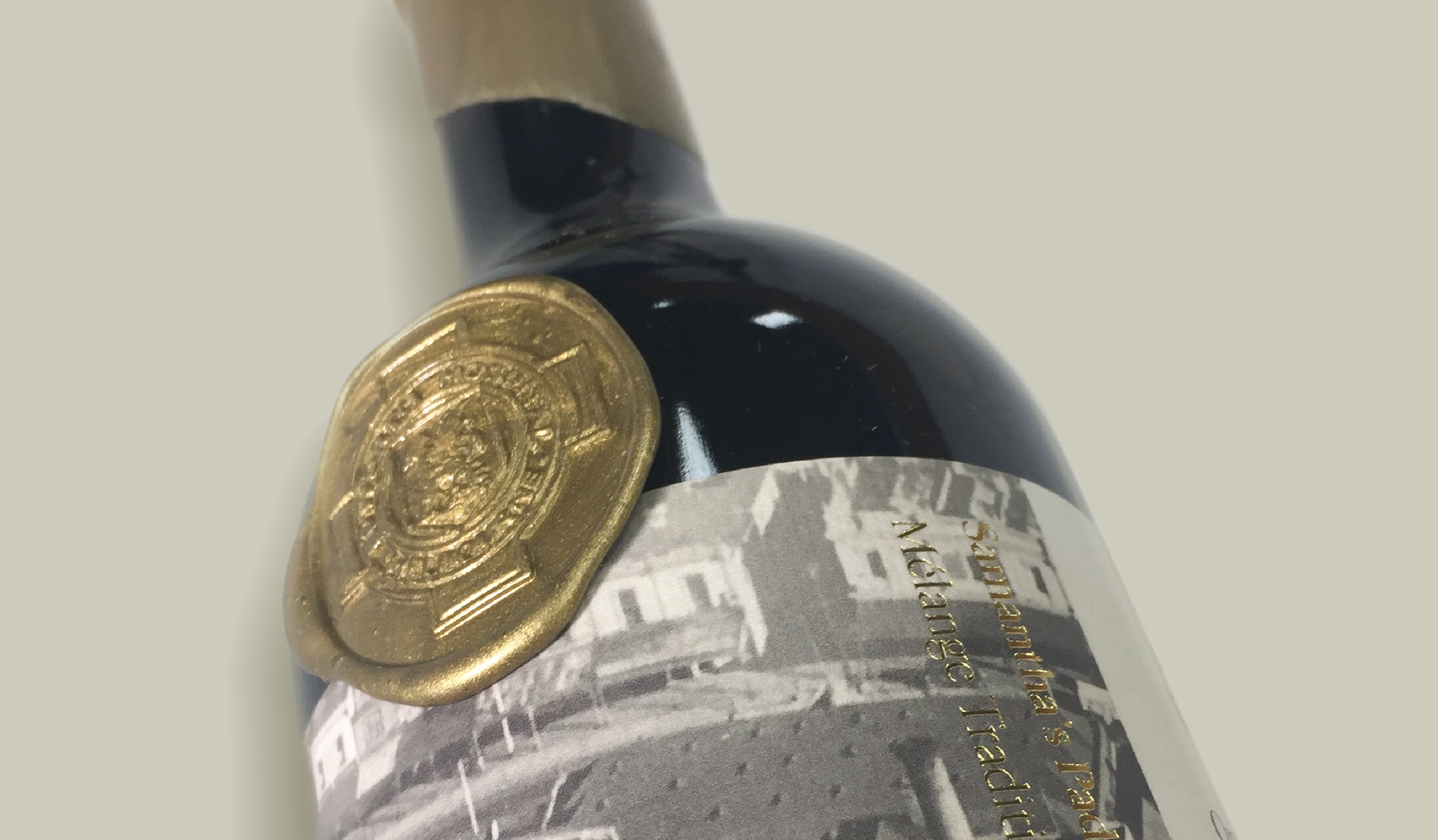 Close-up of a wine bottle with a gold foil seal and partially visible label.