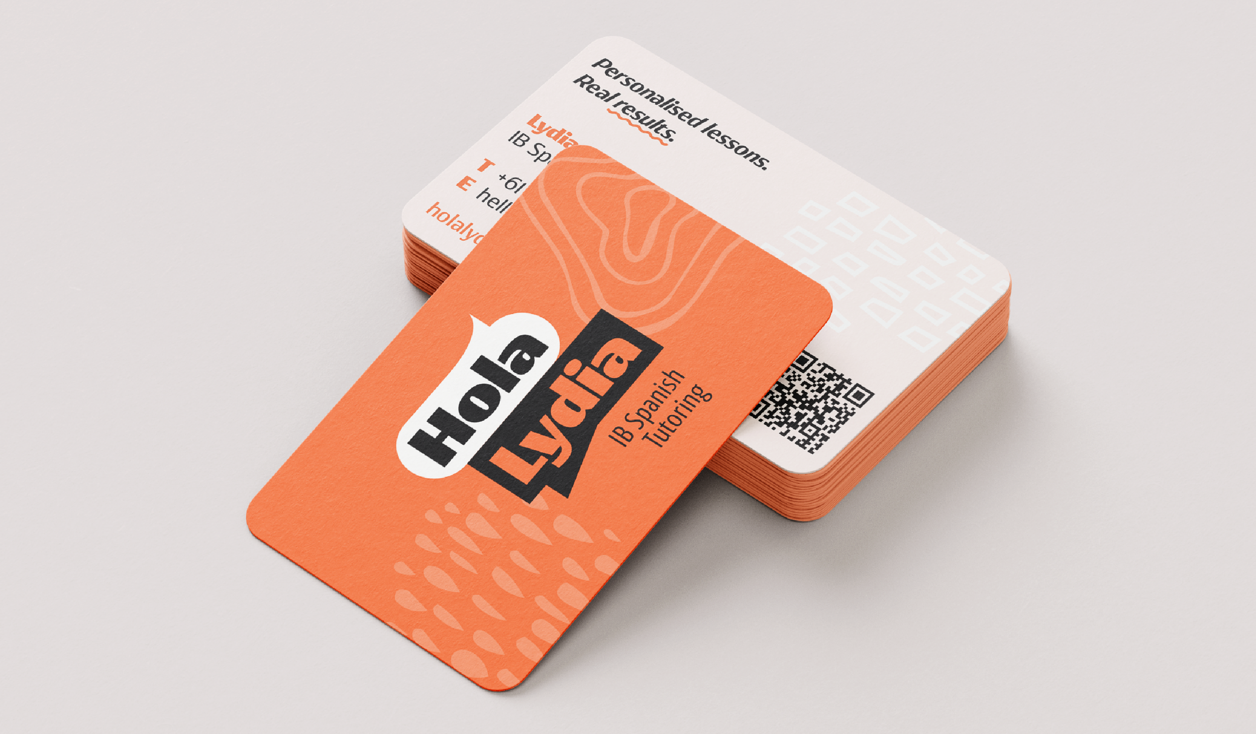 A stack of business cards for Holly Lydia IB Spanish Tutoring, with an orange and white color scheme and a QR code.