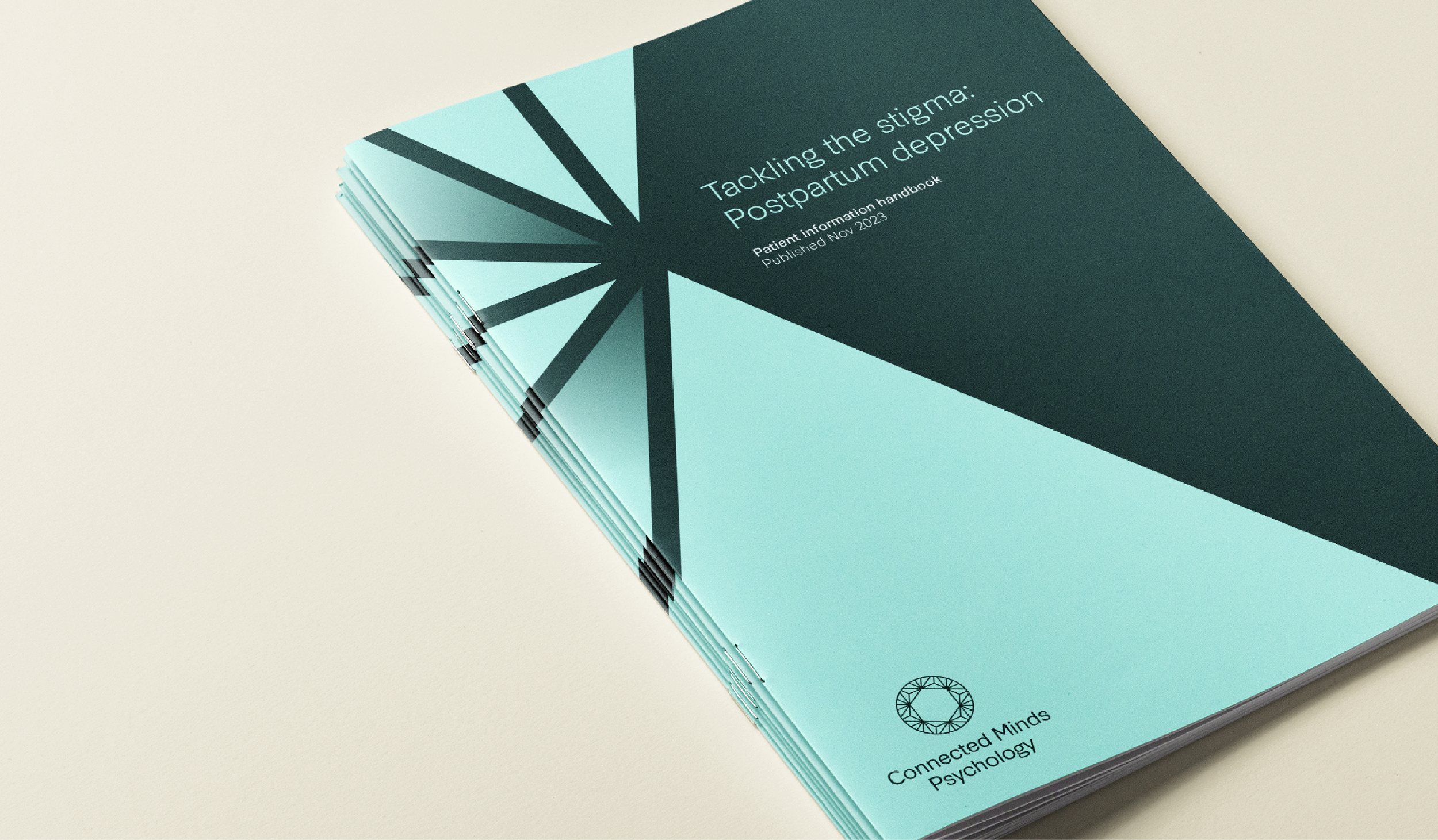 Stack of booklets titled "Tackling the stigma: Postpartum depression. Patient information handbook. Published Nov 2023." with a geometric teal and dark green cover design.