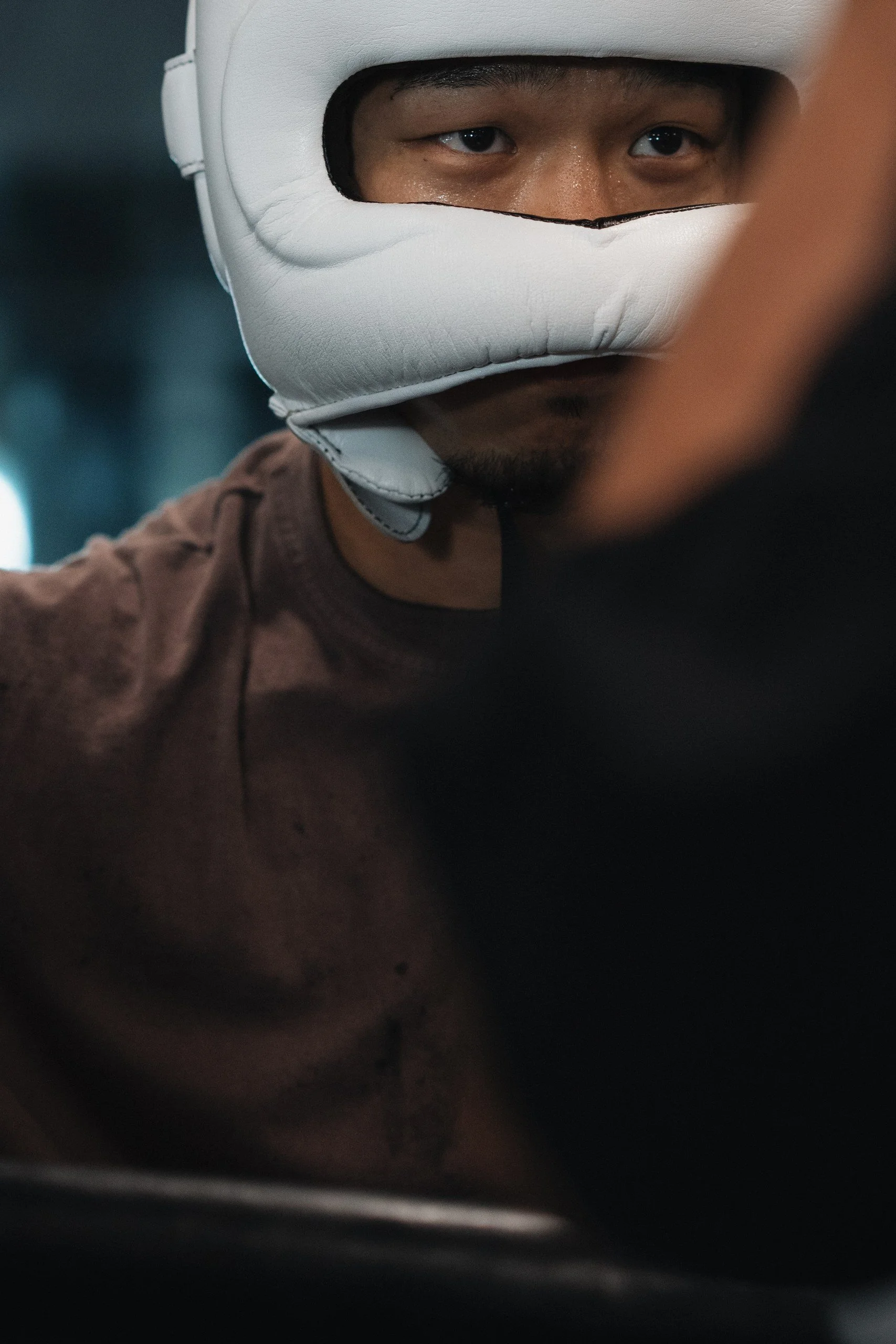 A person wearing a white protective helmet with a face opening, focusing on their eyes and nose, with their face partially covered by the helmet.