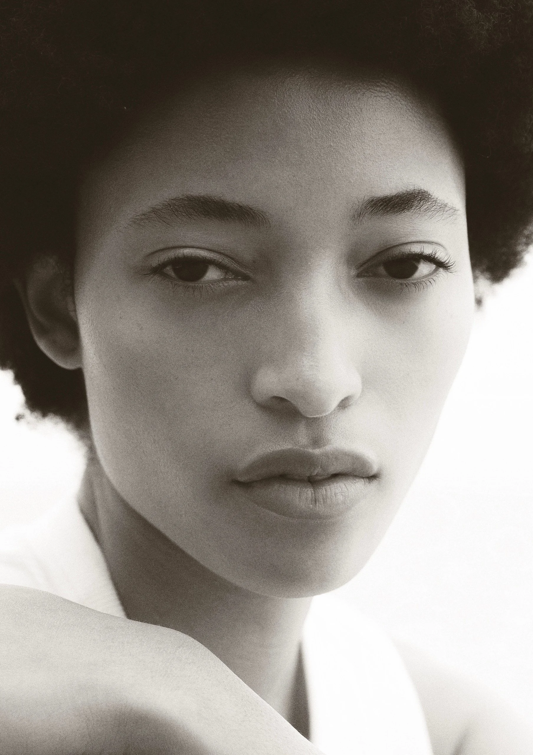 Close-up of a young woman's face with closed eyes, natural hair, and soft expression in black and white.