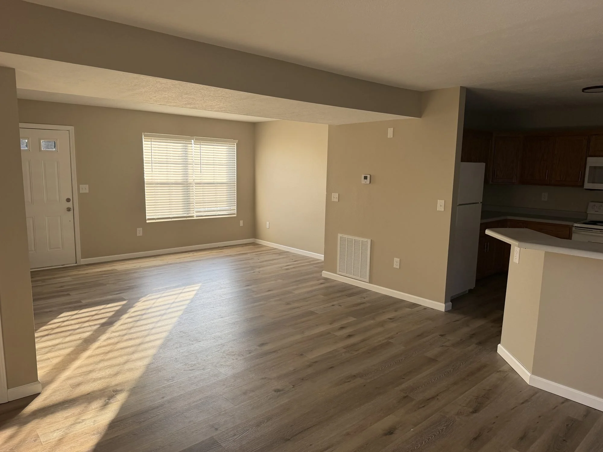  Living room with laminate flooring and large window in this Lebanon, MO rental townhouse. 