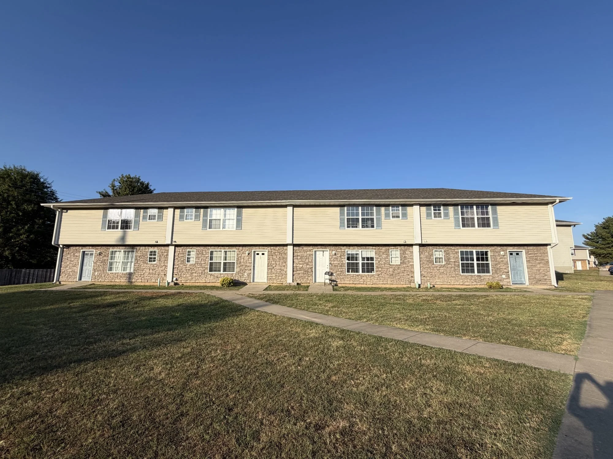  Two-story townhouse for rent in Lebanon, MO, at 1221 Glenridge St., tan siding and front lawn. 