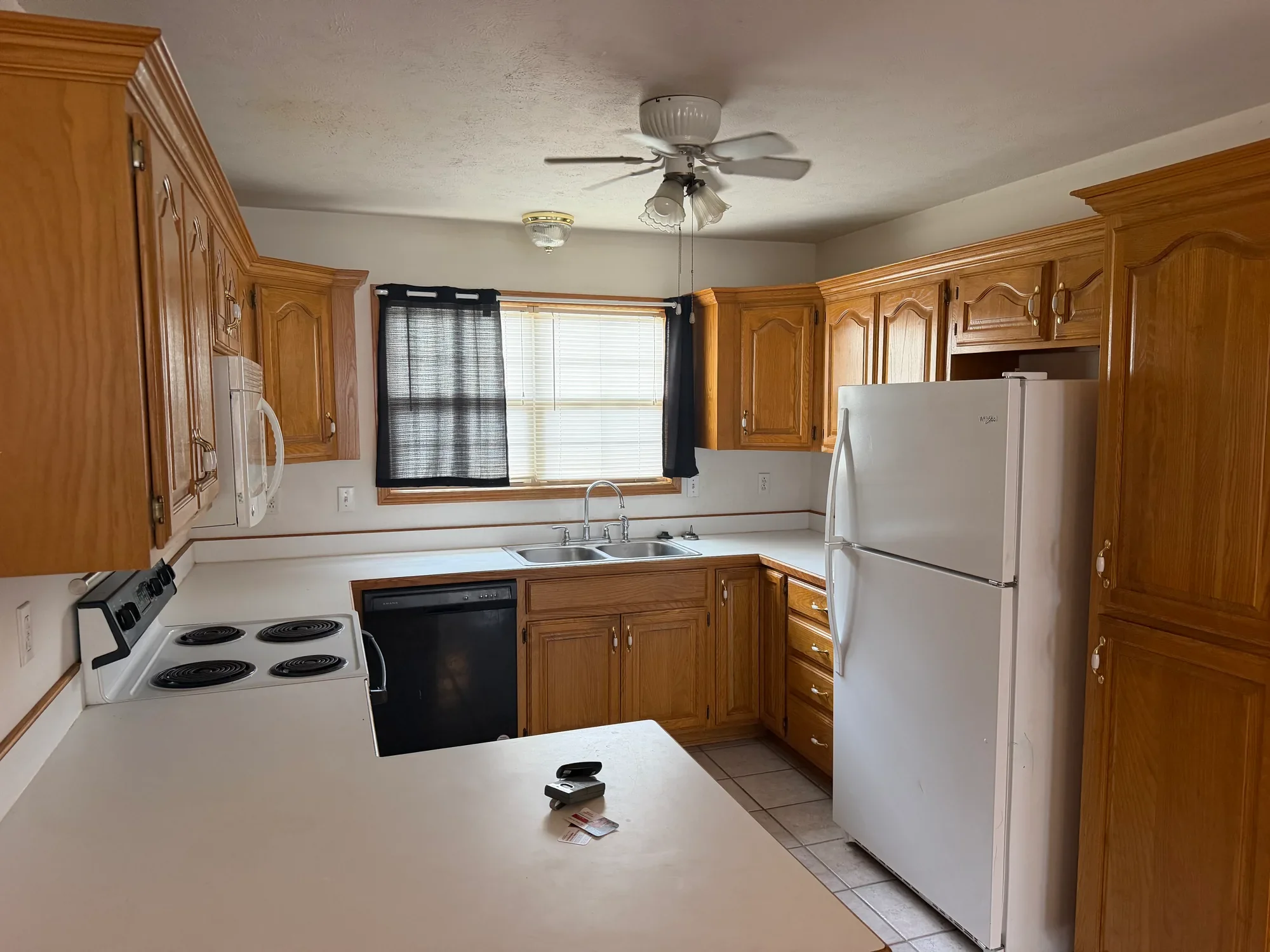  Kitchen with oak cabinets, white refrigerator, range, dishwasher and window over the sink 