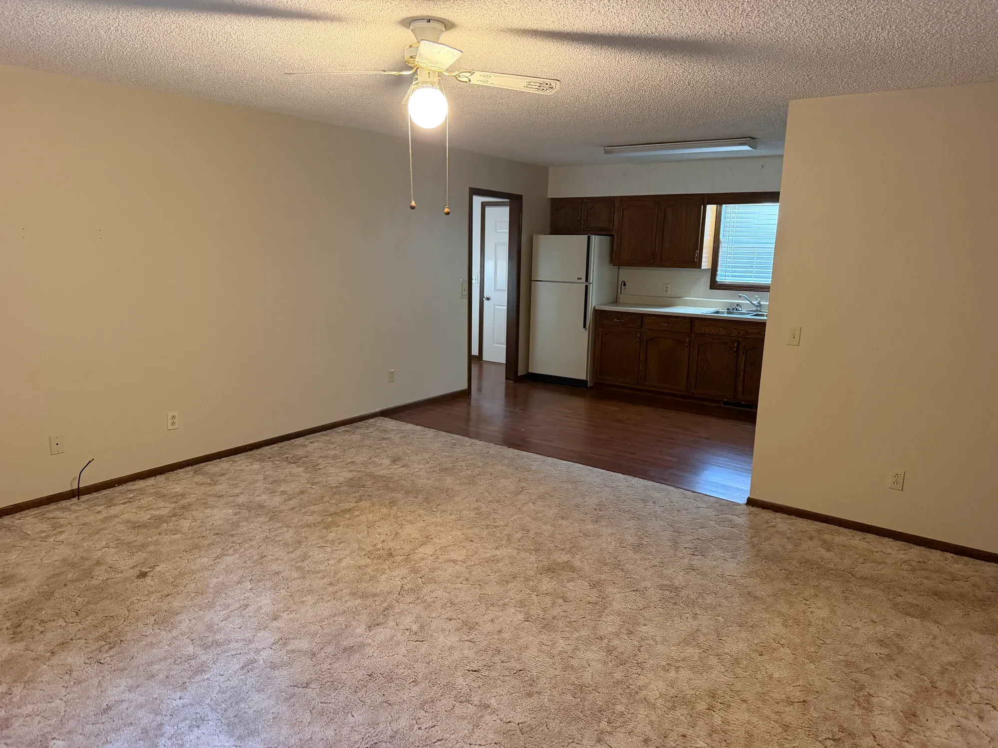  Carpeted living room with ceiling fan, open to the kitchen 