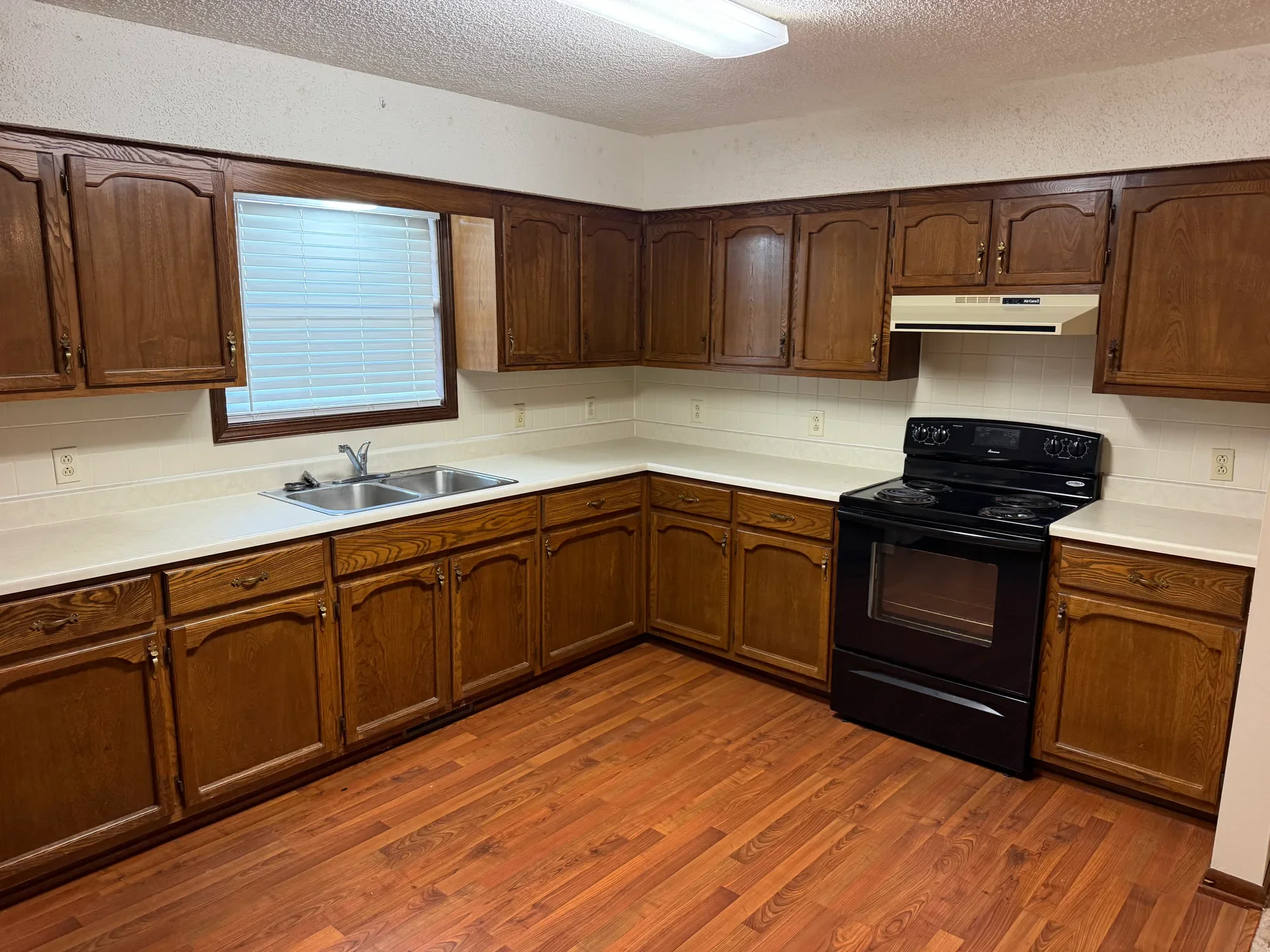  Kitchen with wood cabinets, double sink, and electric range 