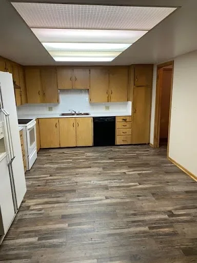  kitchen: Kitchen with wood cabinets, white stove, refrigerator, black dishwasher, and wood-look flooring 