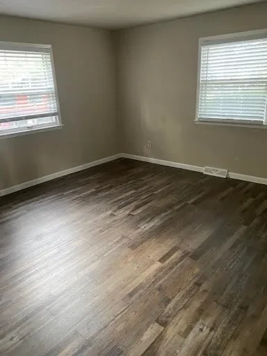  Bedroom with two windows with blinds and dark wood-look flooring 