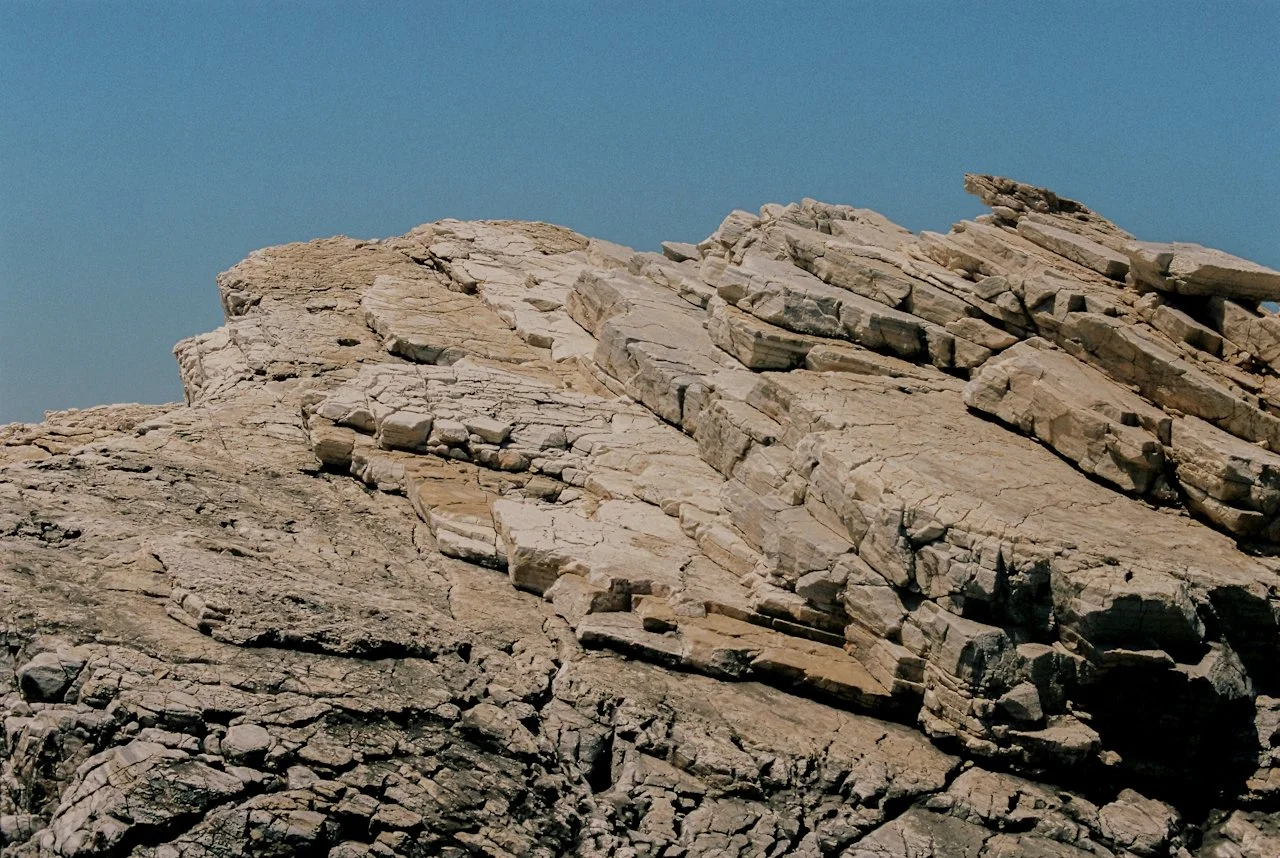 Close-up view of layered, cracked rocks under a clear blue sky.