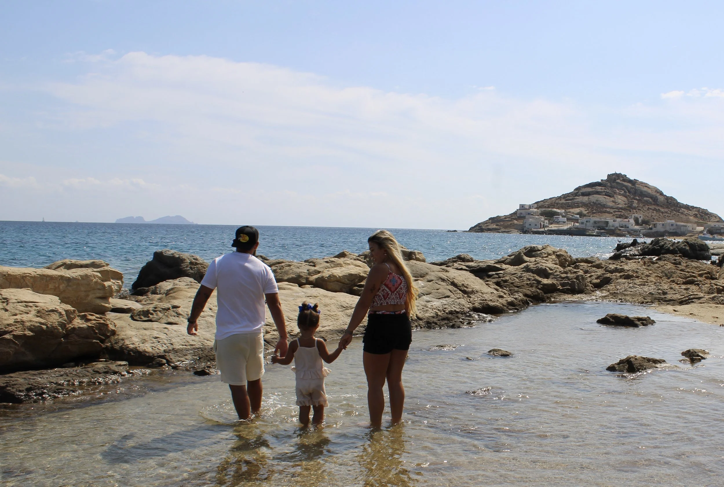 Familia caminando de la mano por una playa rocosa durante sus vacaciones.