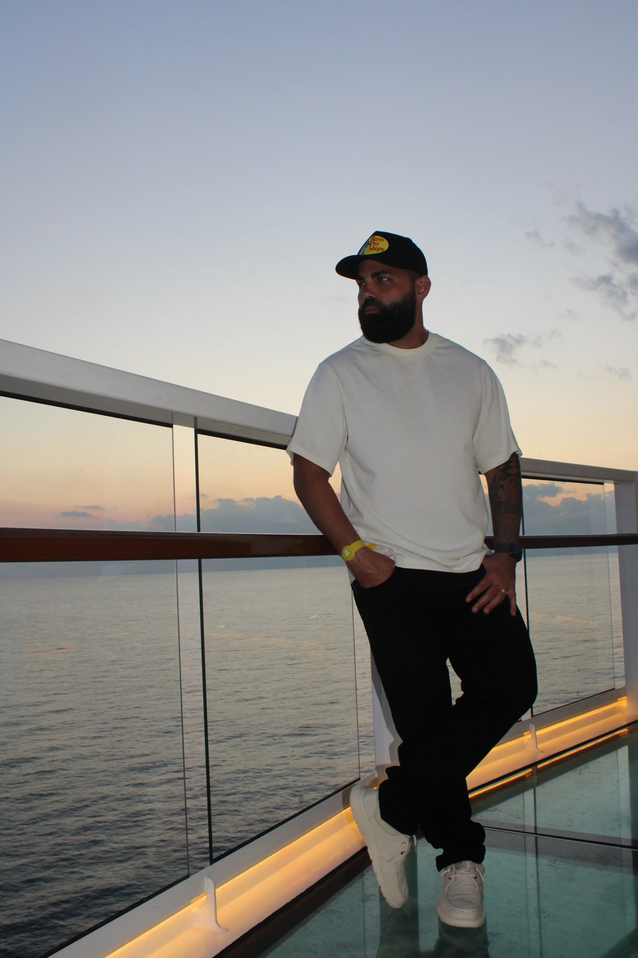 Hombre de pie en la cubierta de un barco al atardecer.