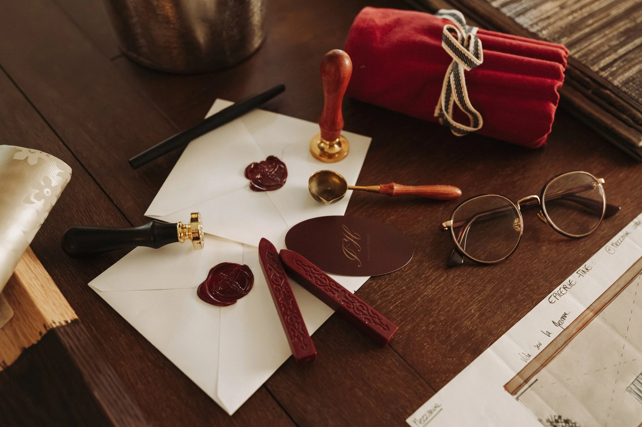 Beautiful details of vintage-style sealing wax, stamps, and wax seals on a dark wooden table, along with a handwritten note.