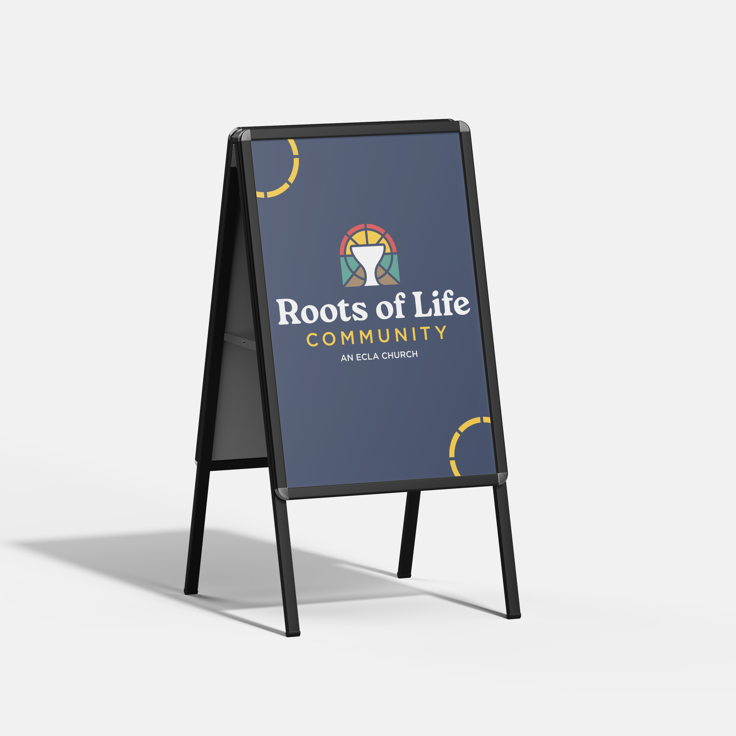 A black foldable A-frame sidewalk sign with a dark blue board displaying the logo and text for Roots of Life Community.