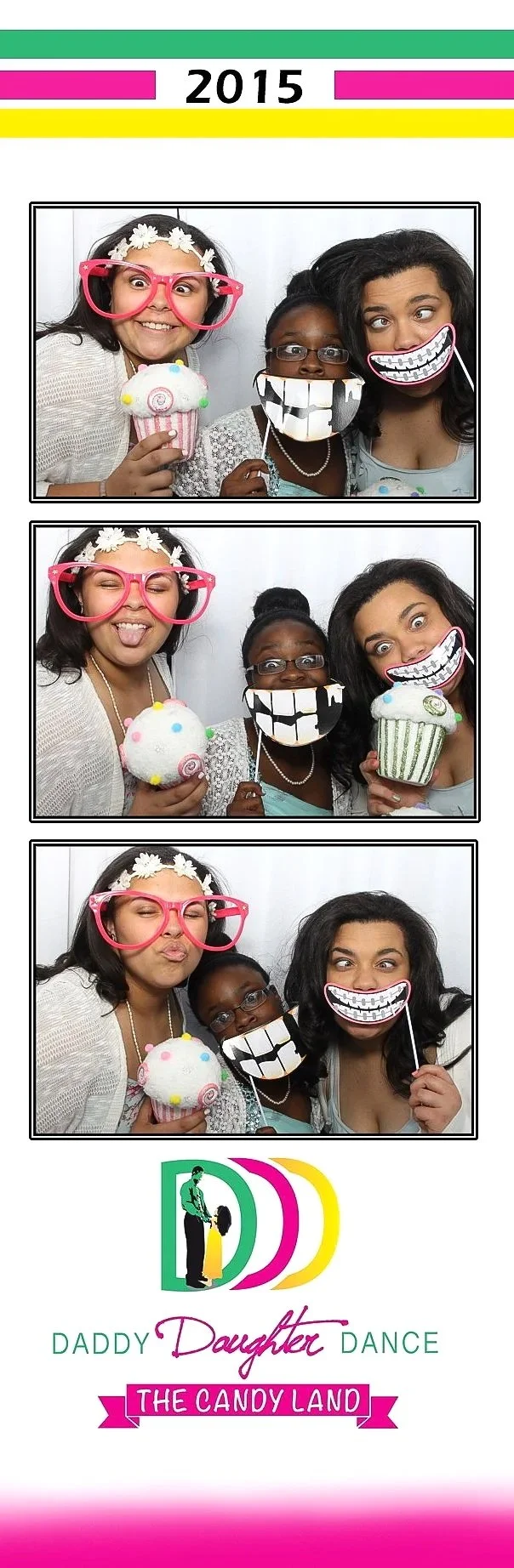 Three women at a Daddy Daughter Dance event with fun photo booth props, including large smiling mouths, glasses, and cupcakes.