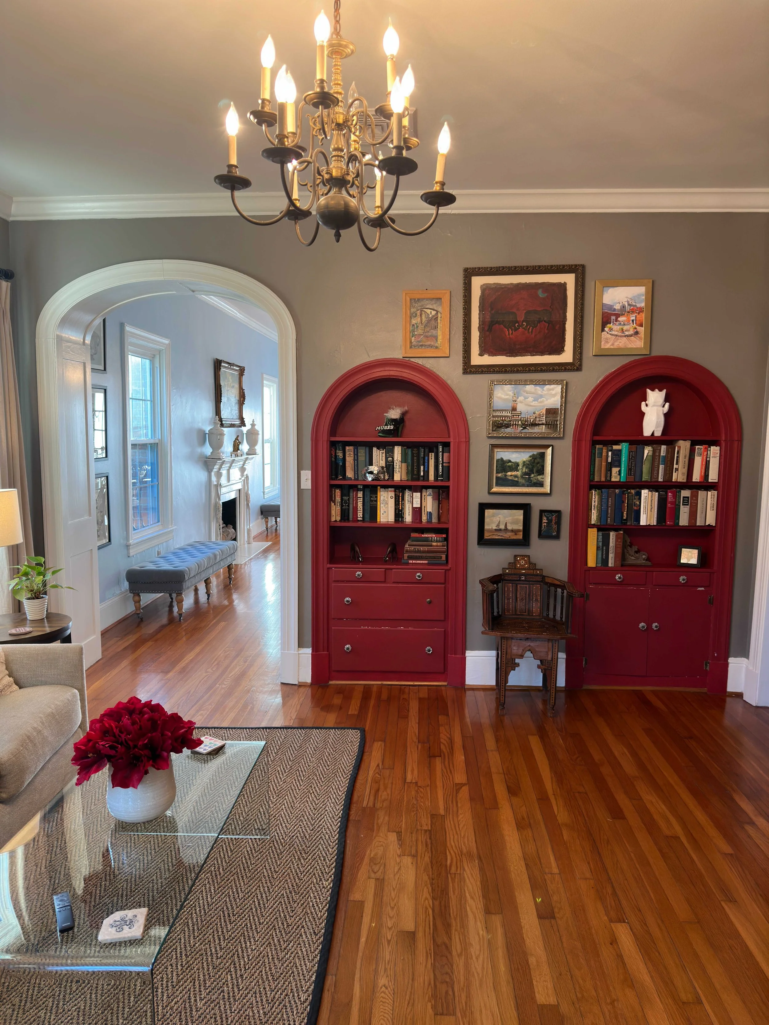 Sitting room with red arched built-in bookcases and gallery wall of art at Amelie Beau