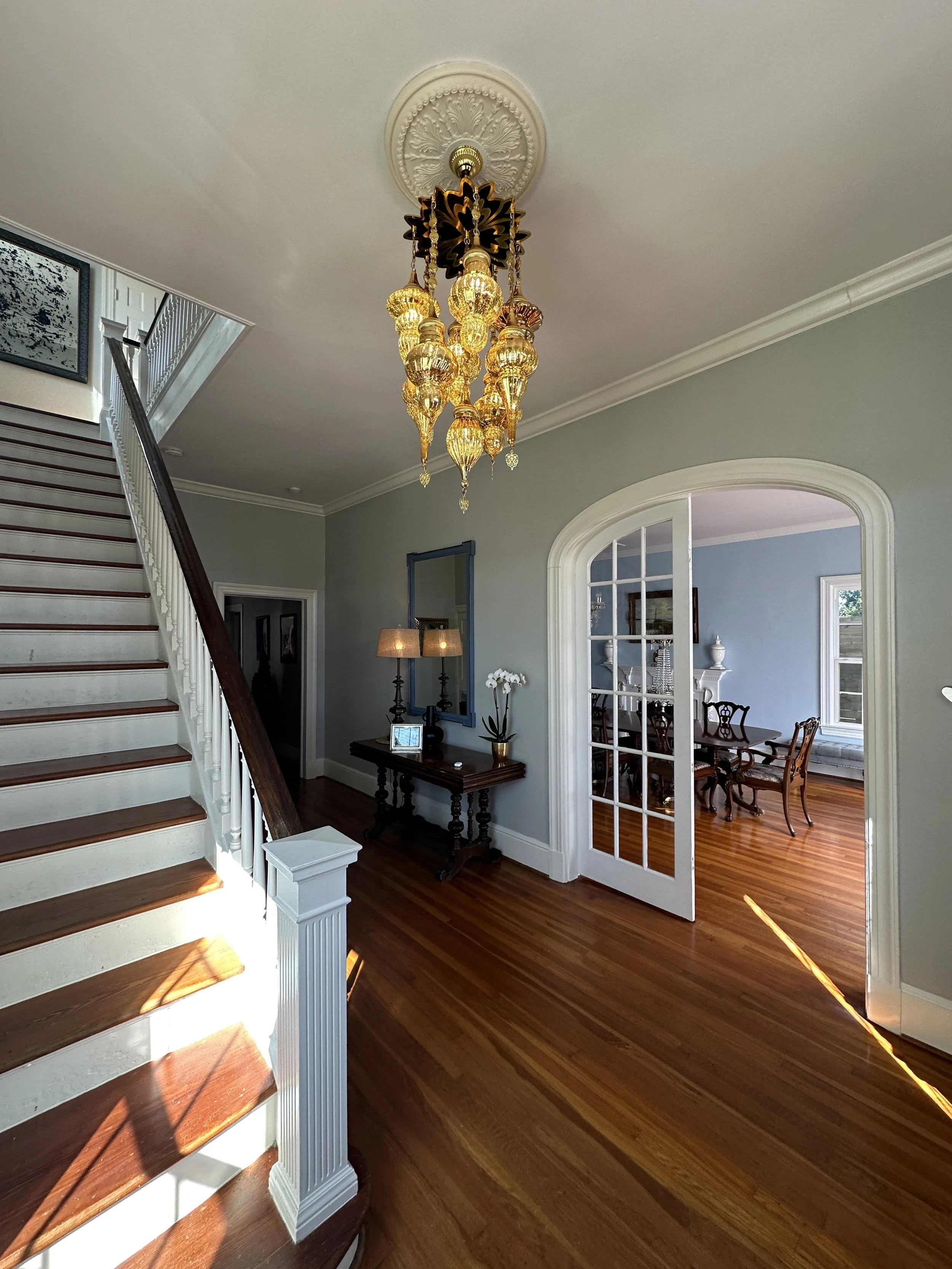 Grand entry foyer with staircase and ornate gold chandelier at Amelie Beau venue