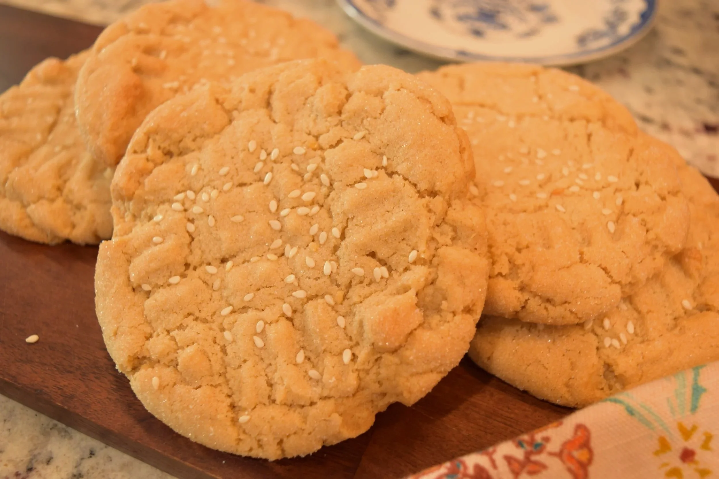 Tahini cookies topped with sesame seeds on a wooden board