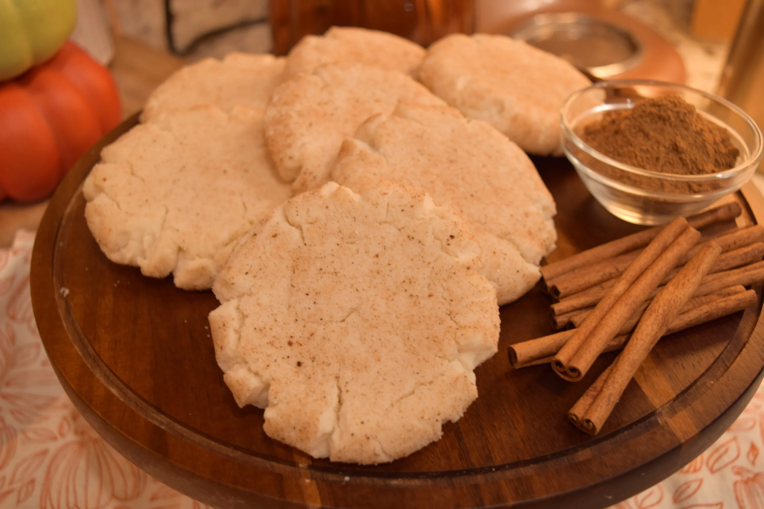 Baharat snickerdoodles with cinnamon sticks and a bowl of spice on a wooden board