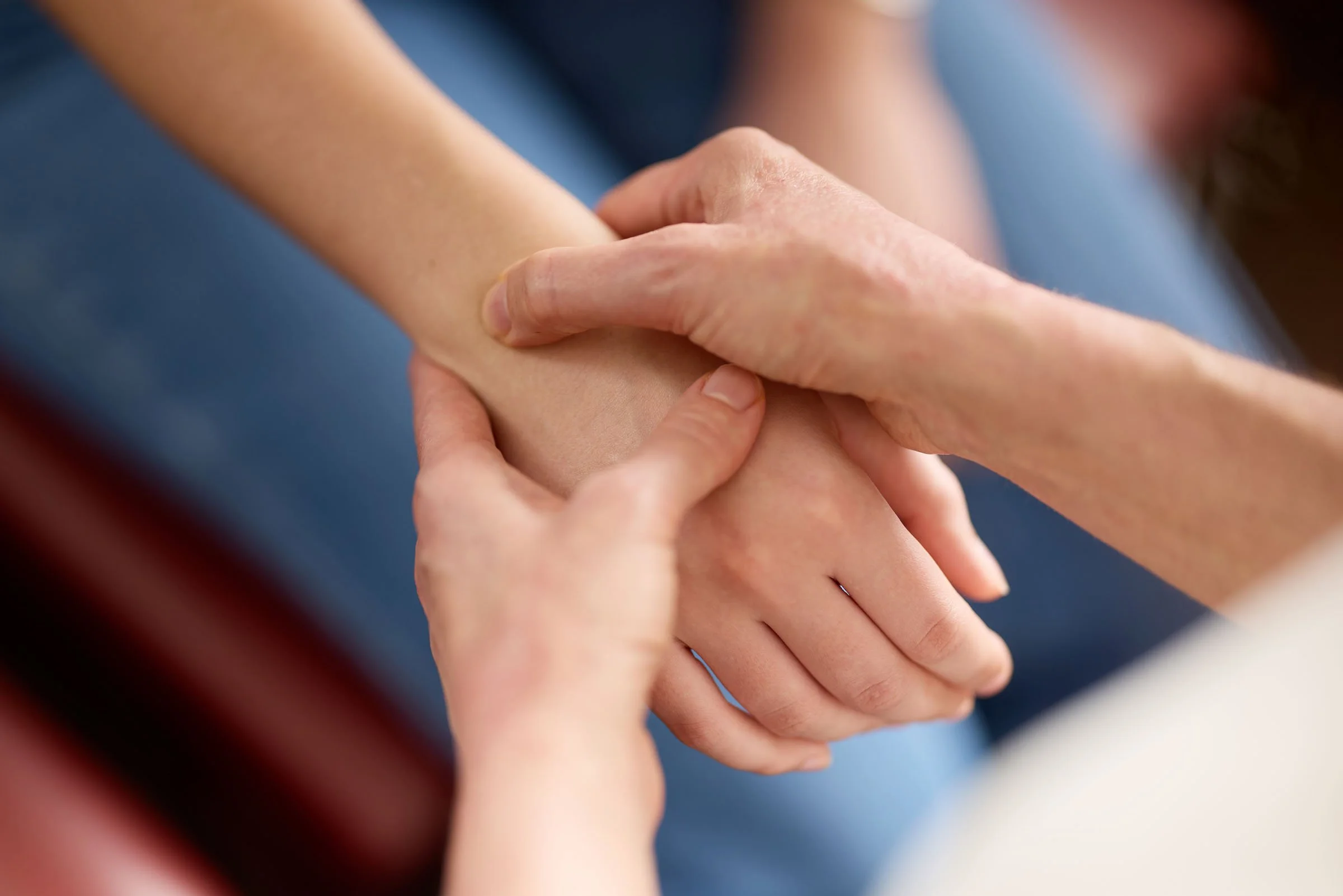 Close-up of a person's hand holding a child's arm as part of a therapy or massage session.